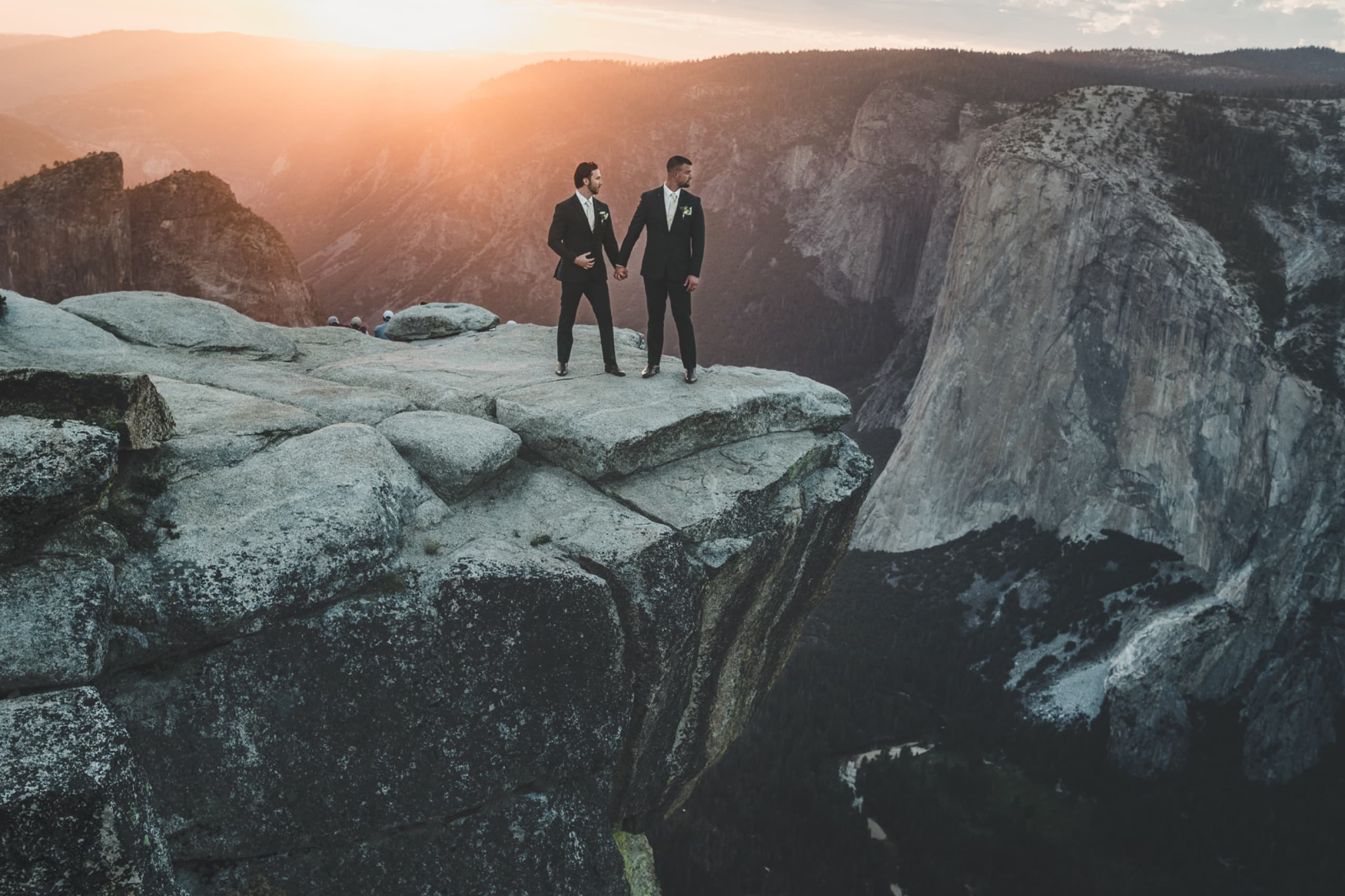 Couple holding hands on the edge of Taft Point in Yosemite at sunset — adventure elopements