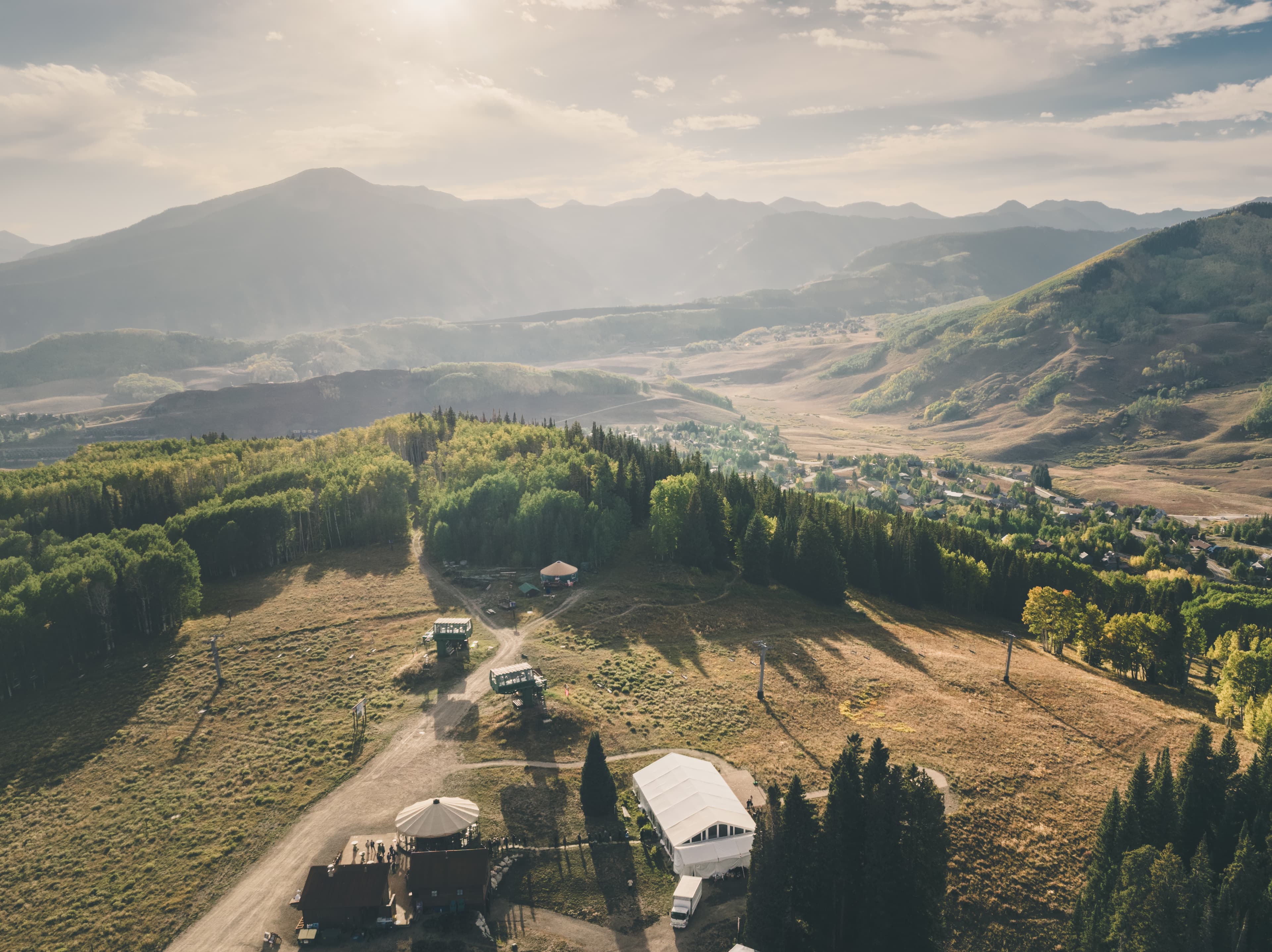 Aerial drone view of Ten Peaks Lodge mid-mountain wedding venue at Crested Butte Mountain Resort, valley and Elk Mountains beyond at golden hour