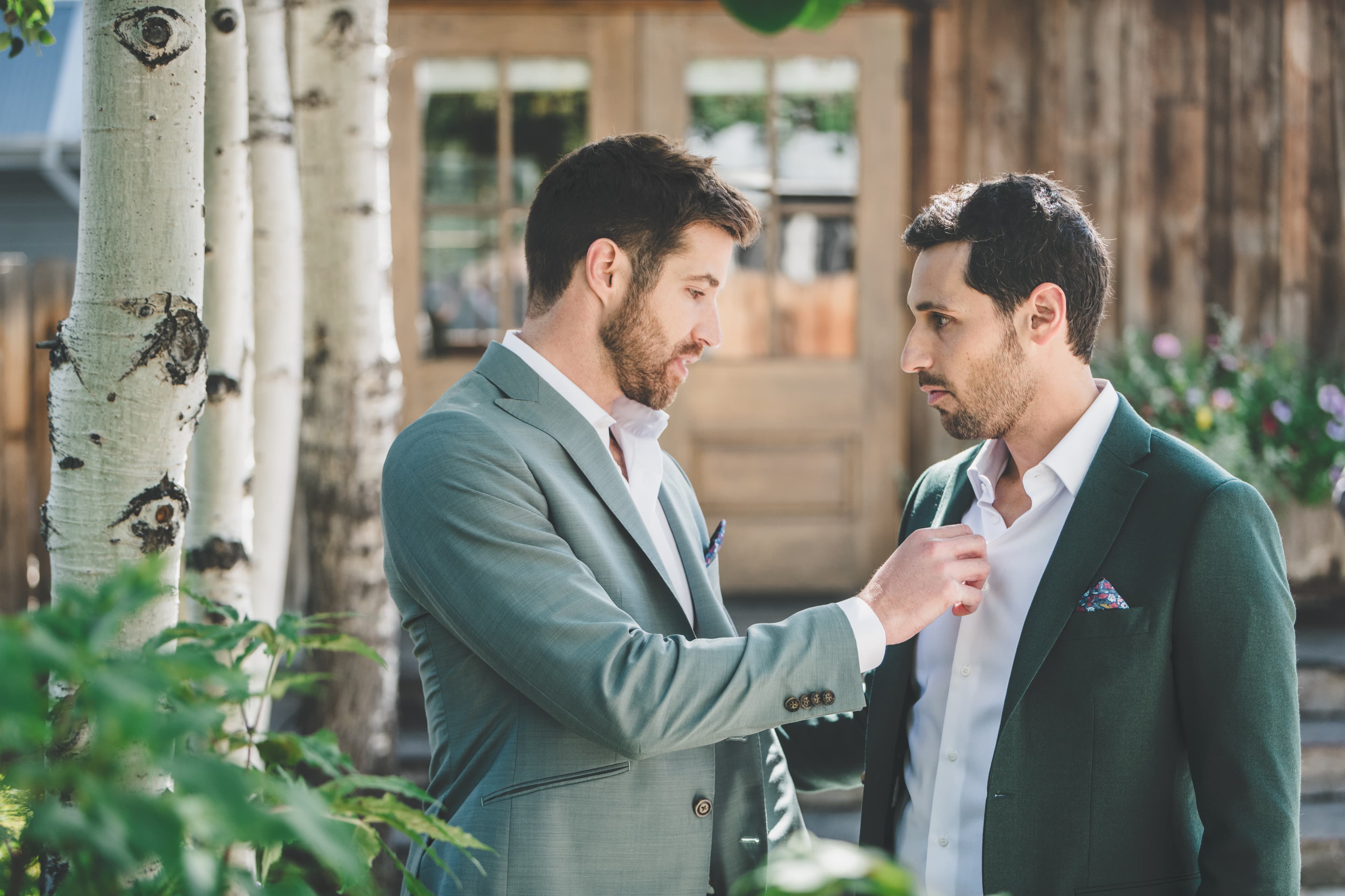 Greg and John adjusting each other's shirts among the aspens before the ceremony