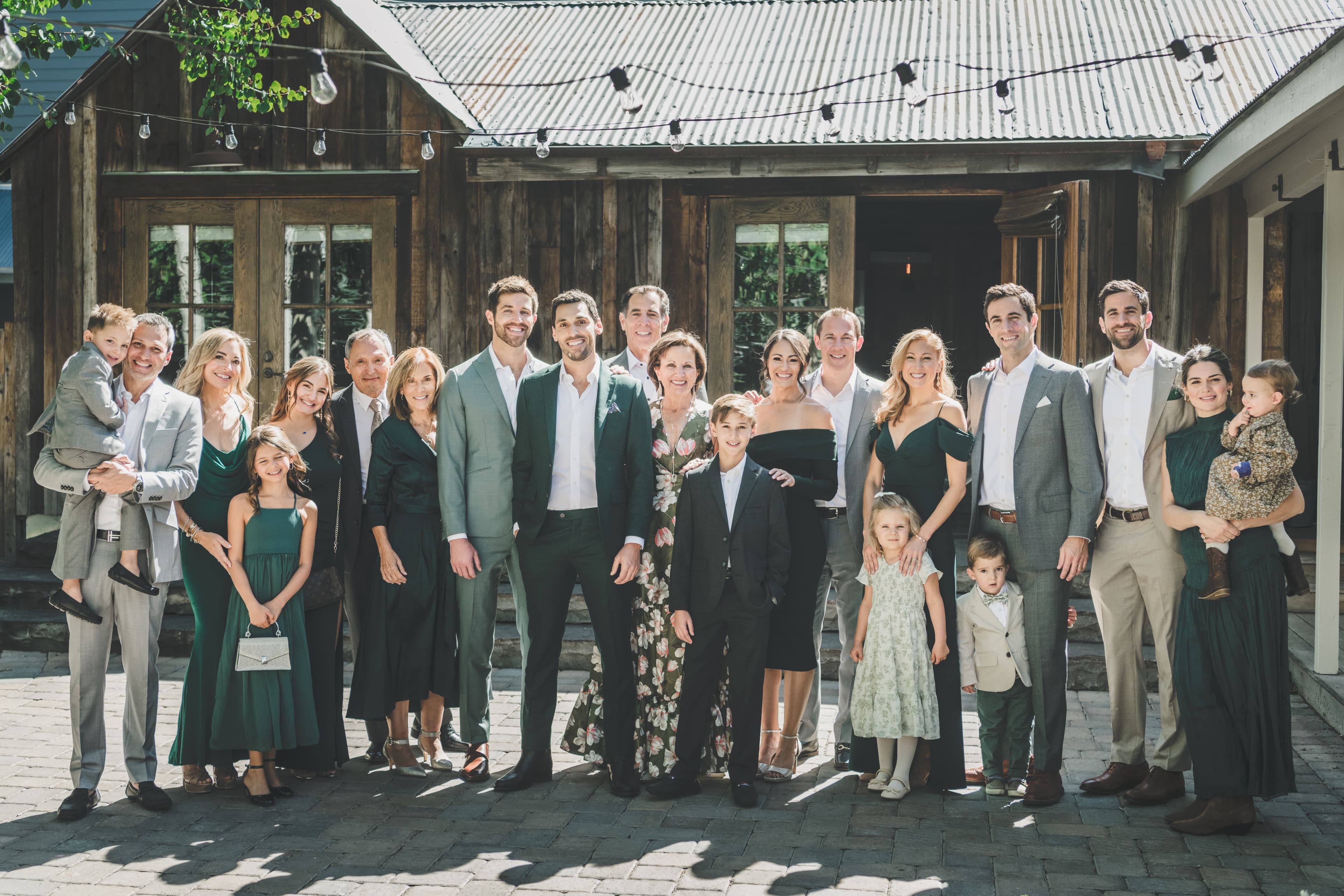 Greg and John surrounded by their family and wedding party in front of a rustic wooden building in Crested Butte