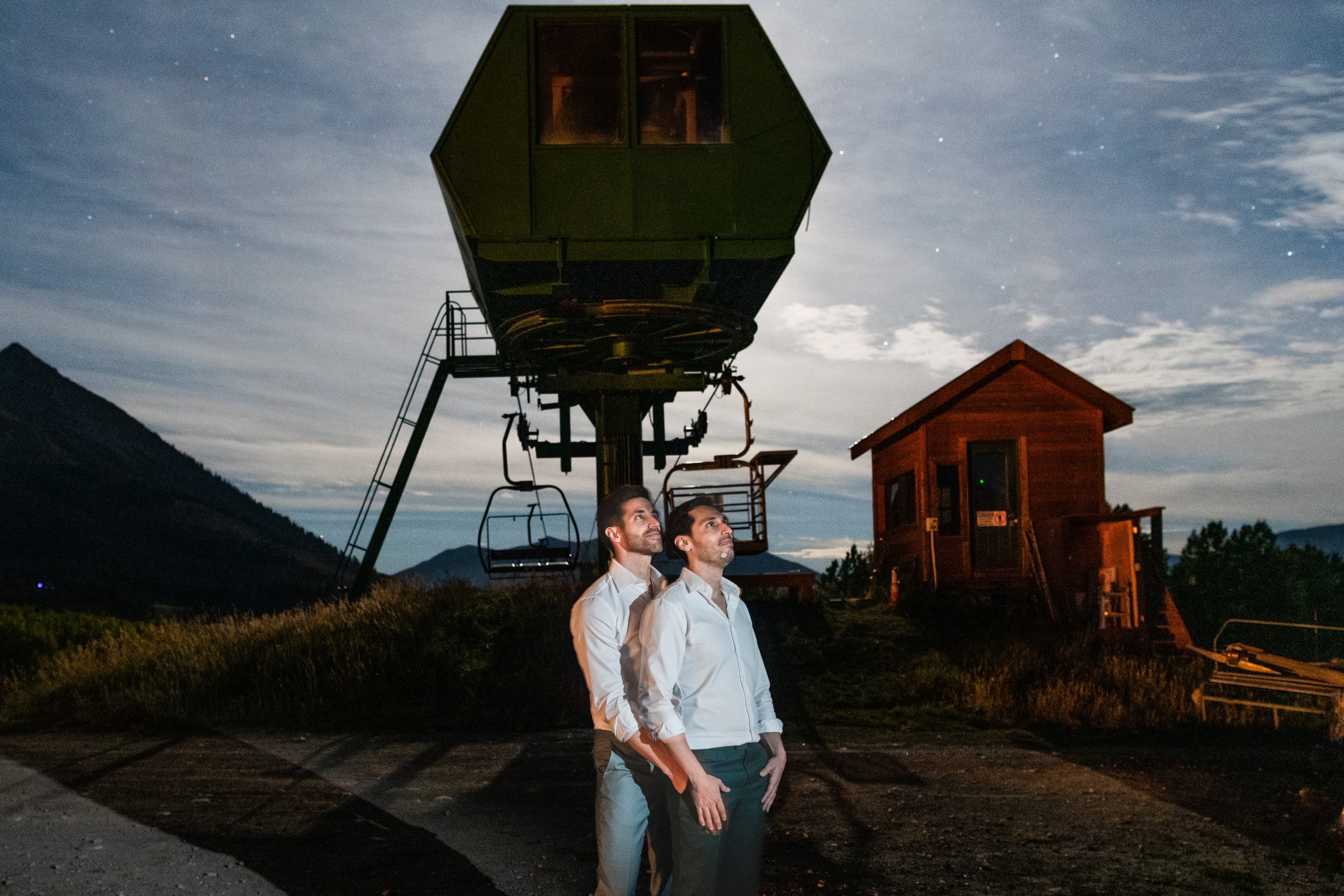 Night portrait of Greg and John under the Ten Peaks chairlift station with stars visible above