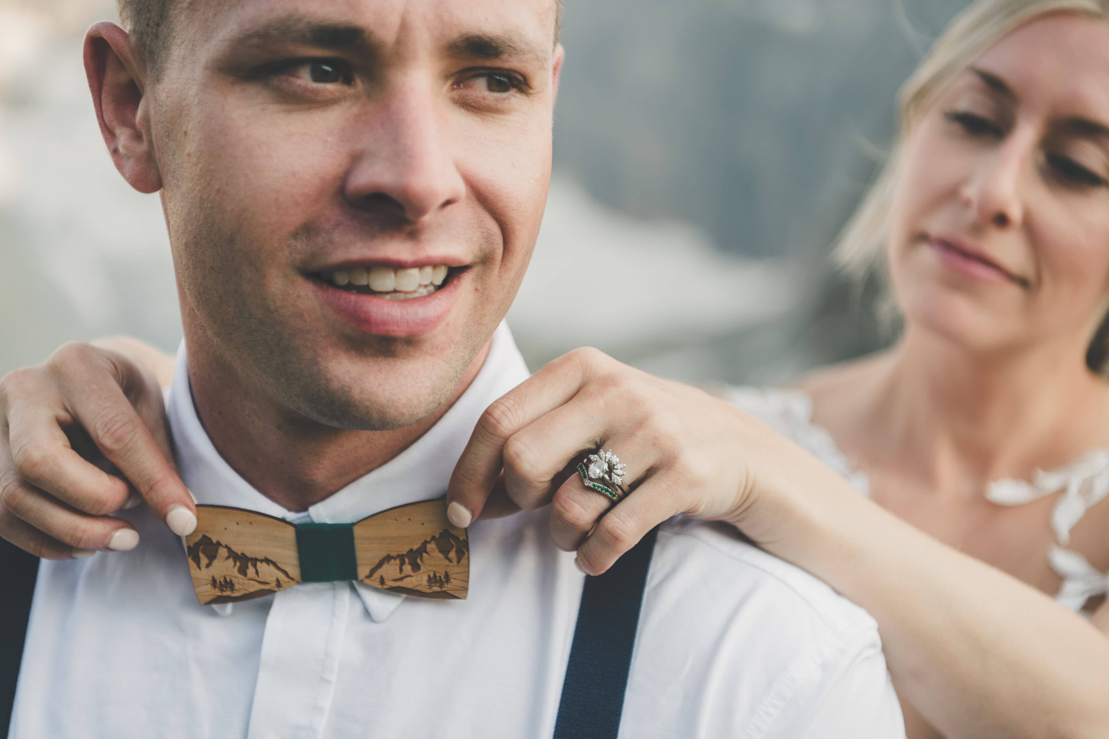 Close-up of Shawna fixing Ryan's hand-carved wood mountain bow tie before their Glacier vows