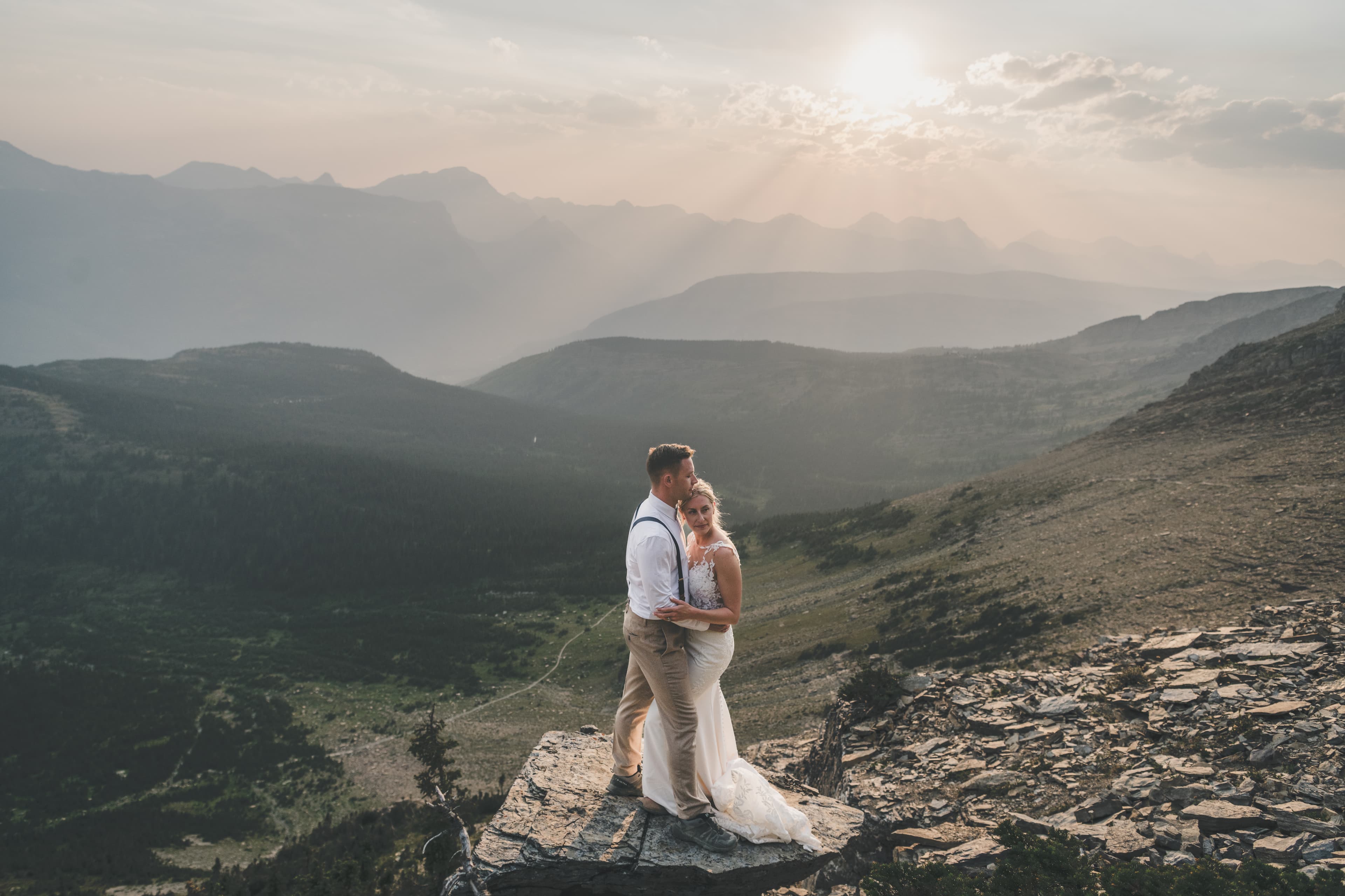 Shawna and Ryan silhouetted in the last light above the Many Glacier valley with a winding trail below