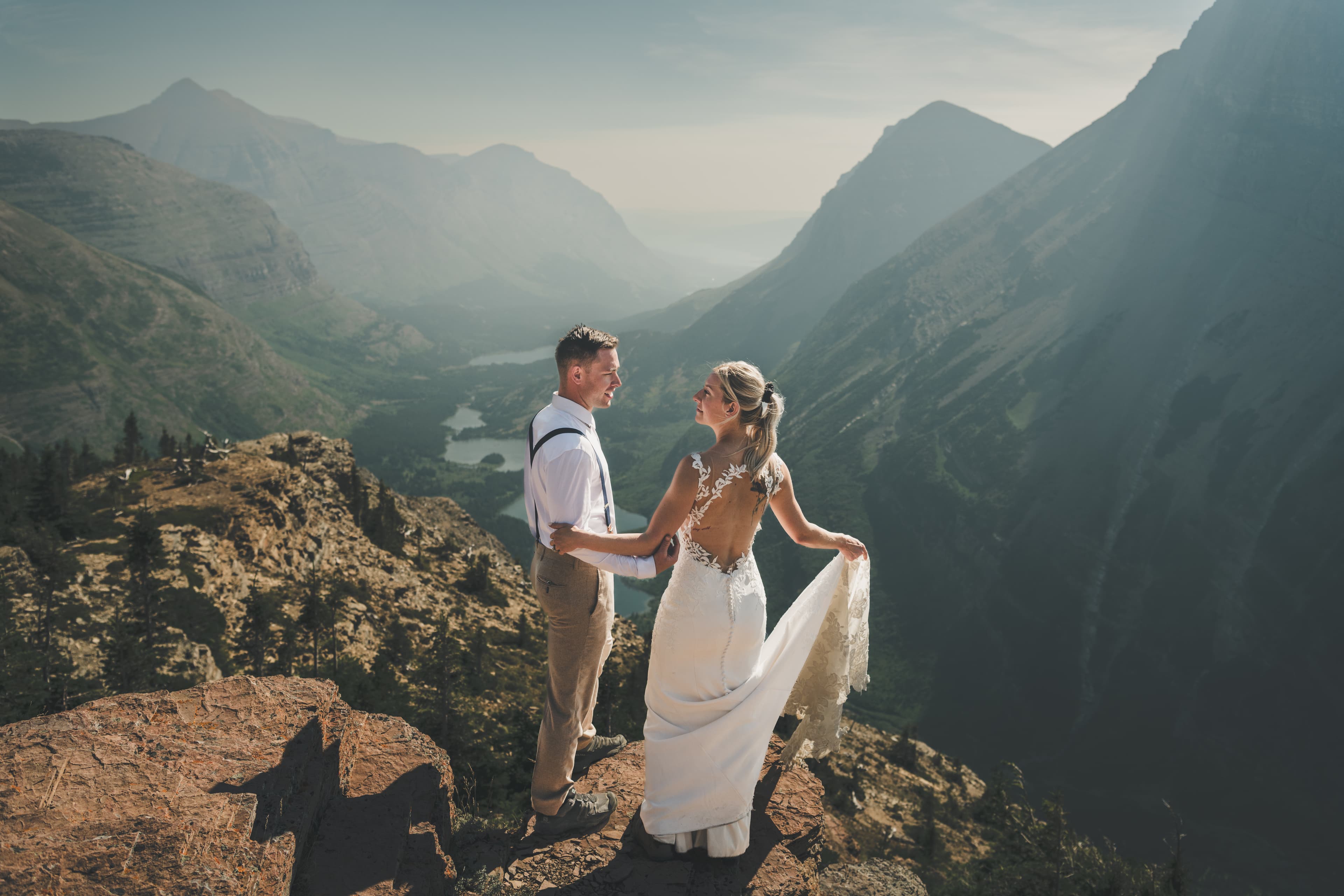 Shawna and Ryan facing each other at the cliff edge as her train trails over the rock and the valley falls away behind