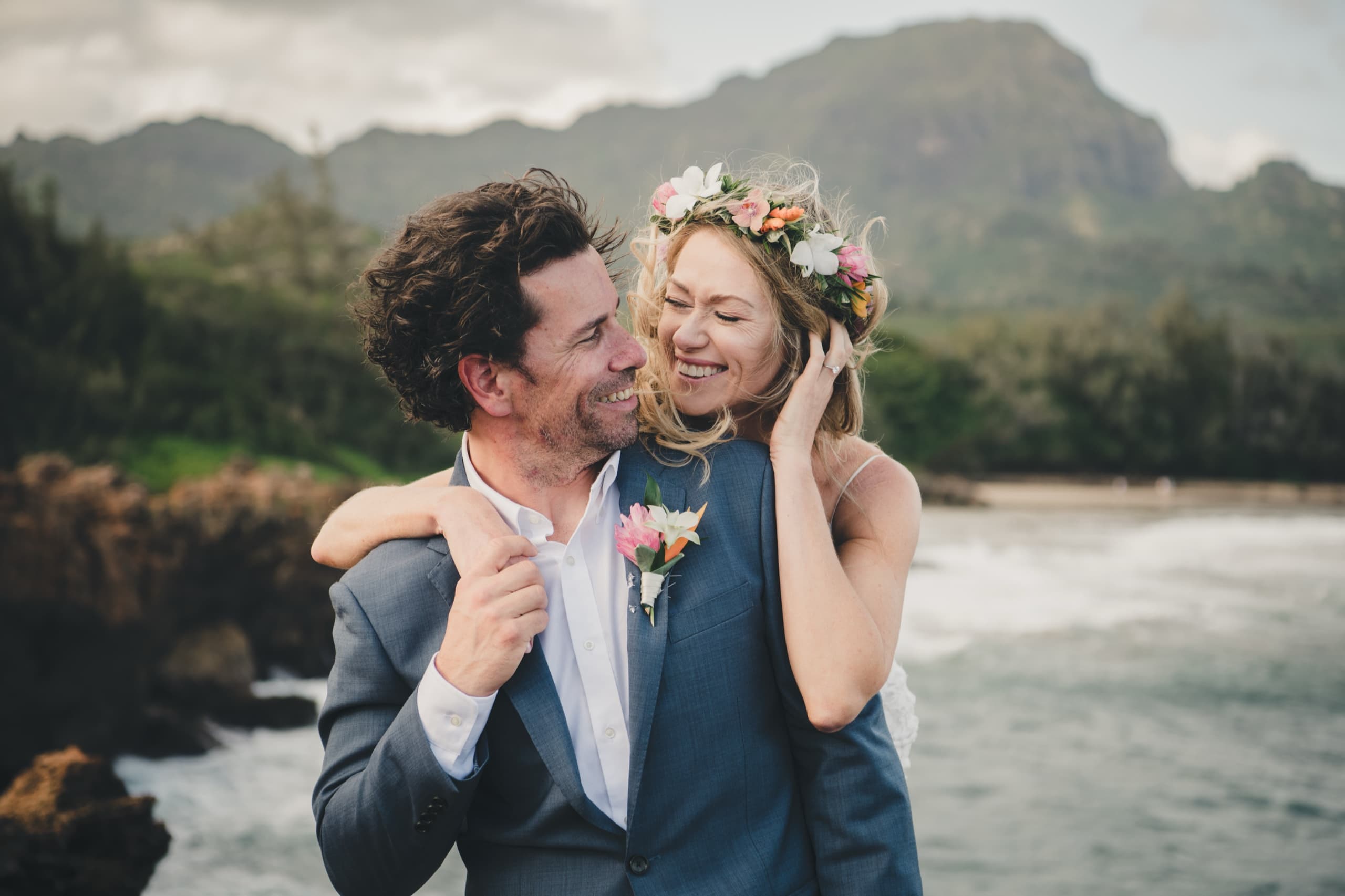 Erin and Kenny kiss in their flower crown and tropical lei on the Kauai coast during their Grand Hyatt elopement