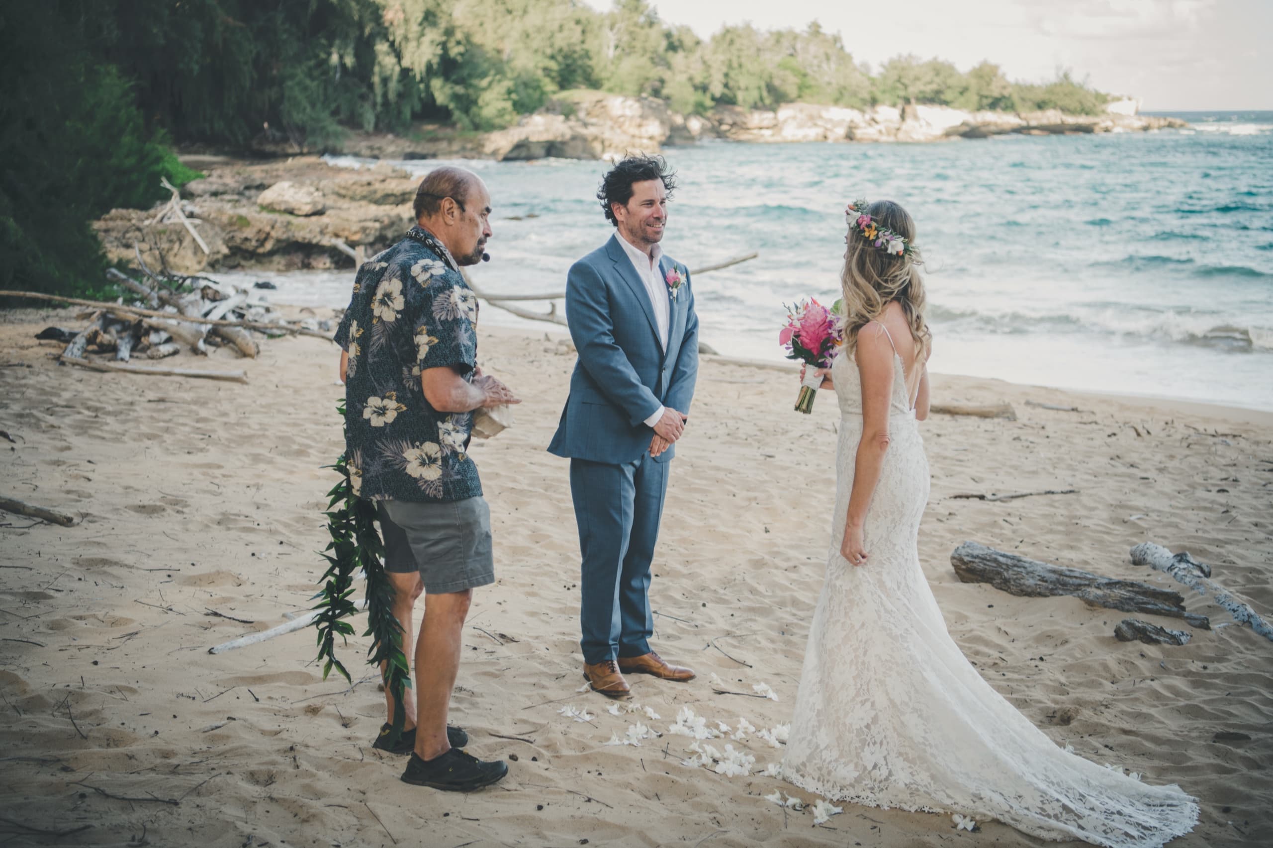 Erin and Kenny at their beach ceremony as the officiant offers a lei in the Hawaiian tradition