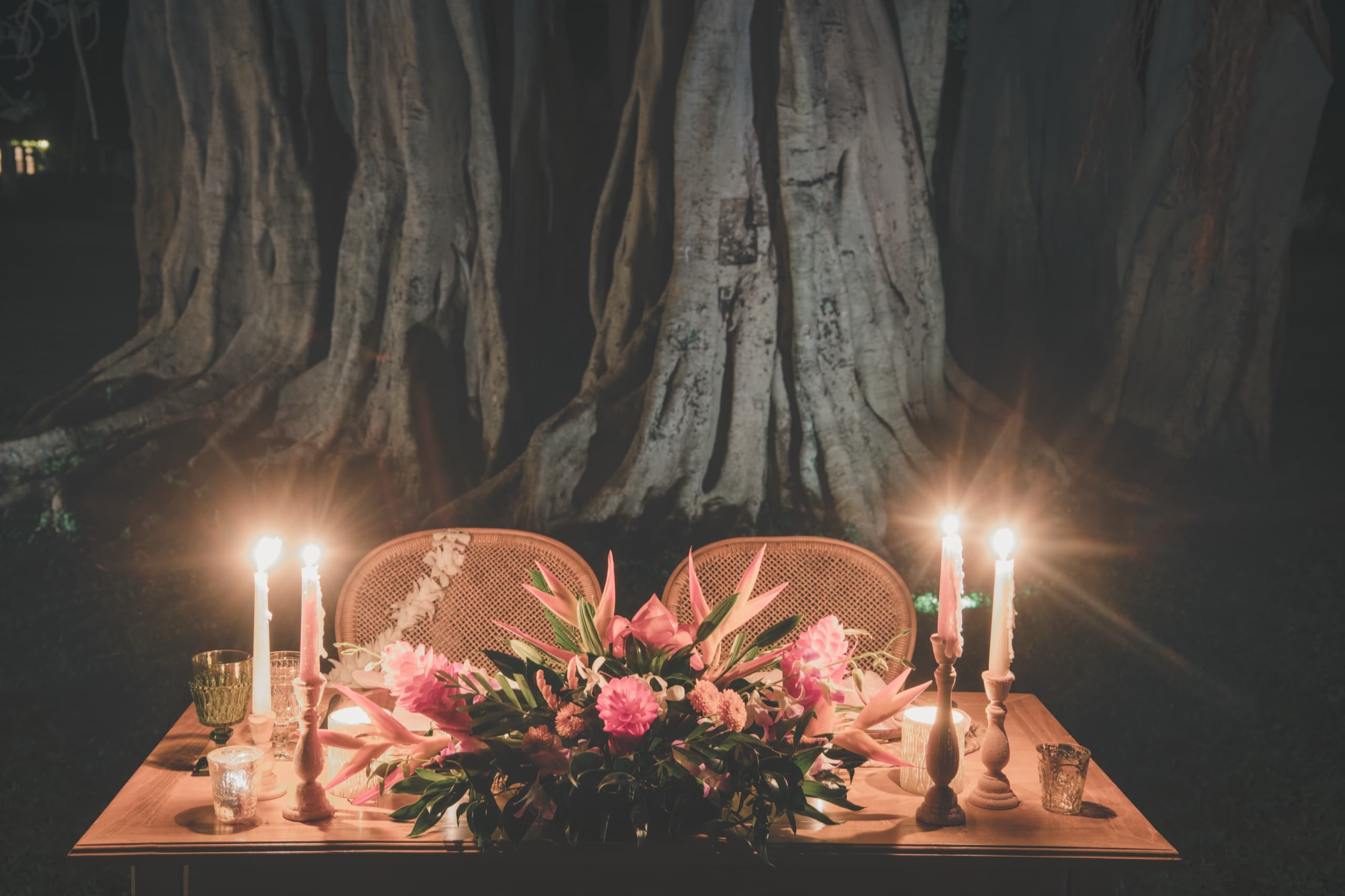 Sweetheart table set under a banyan tree on the Grand Hyatt Kauai grounds, candles lit and waiting
