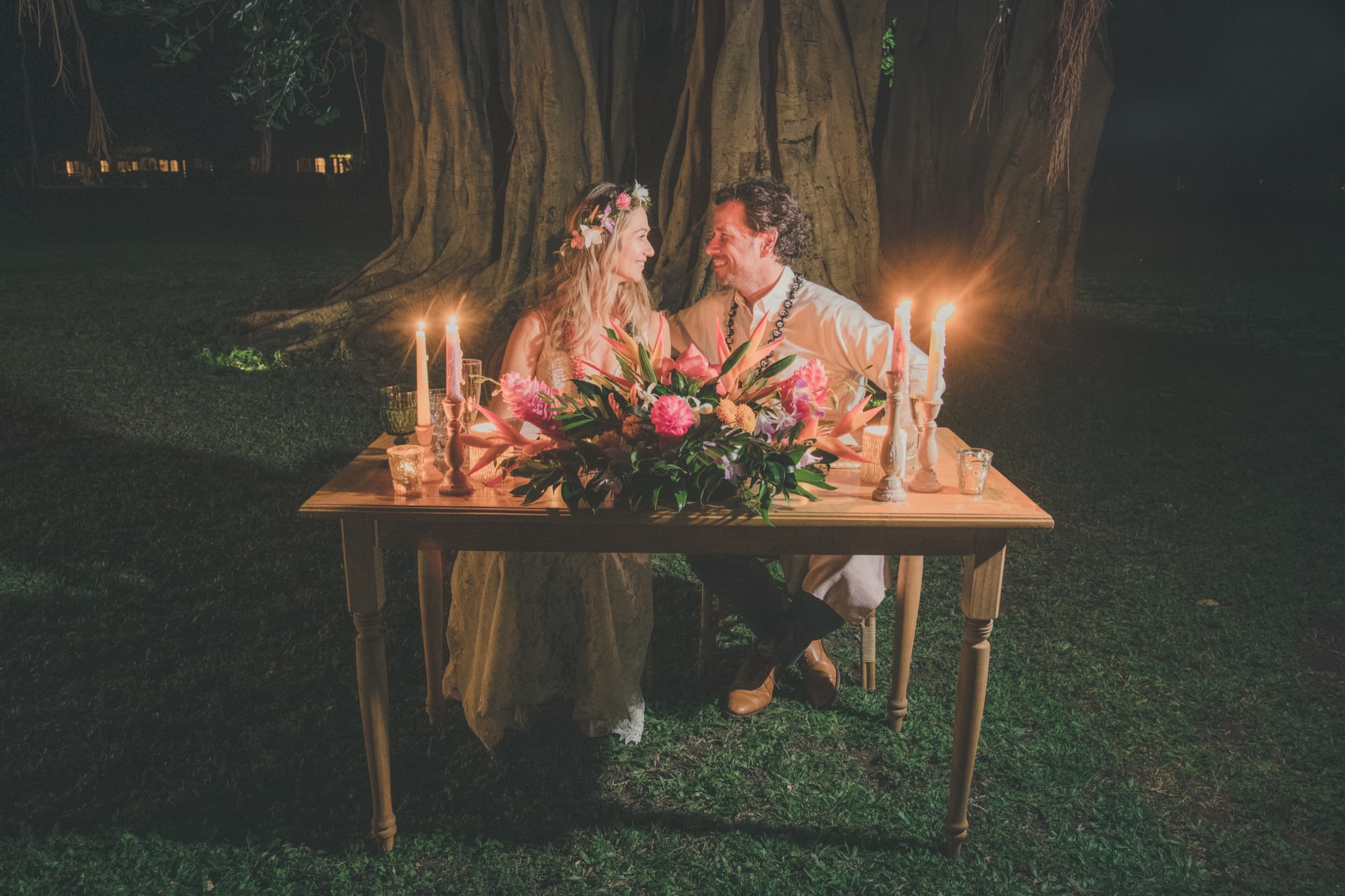Erin and Kenny laughing across their candlelit dinner table beneath the banyan tree at the Grand Hyatt