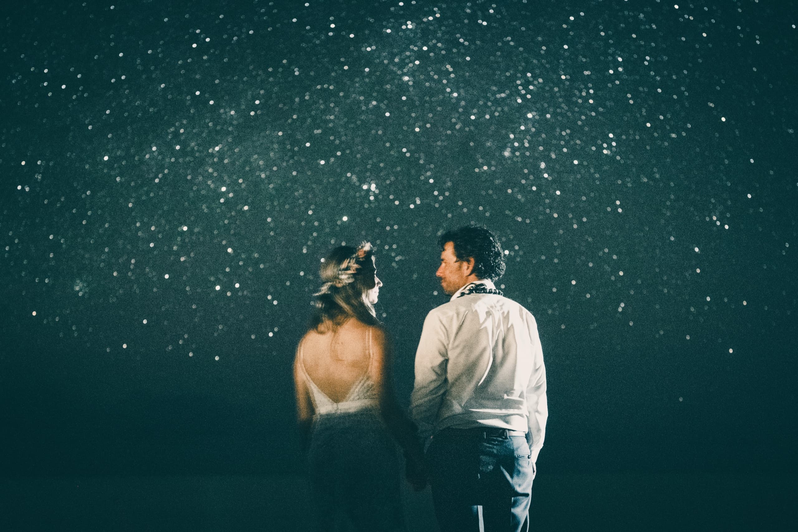 Erin and Kenny holding hands looking up at a field of light on the resort grounds after dinner