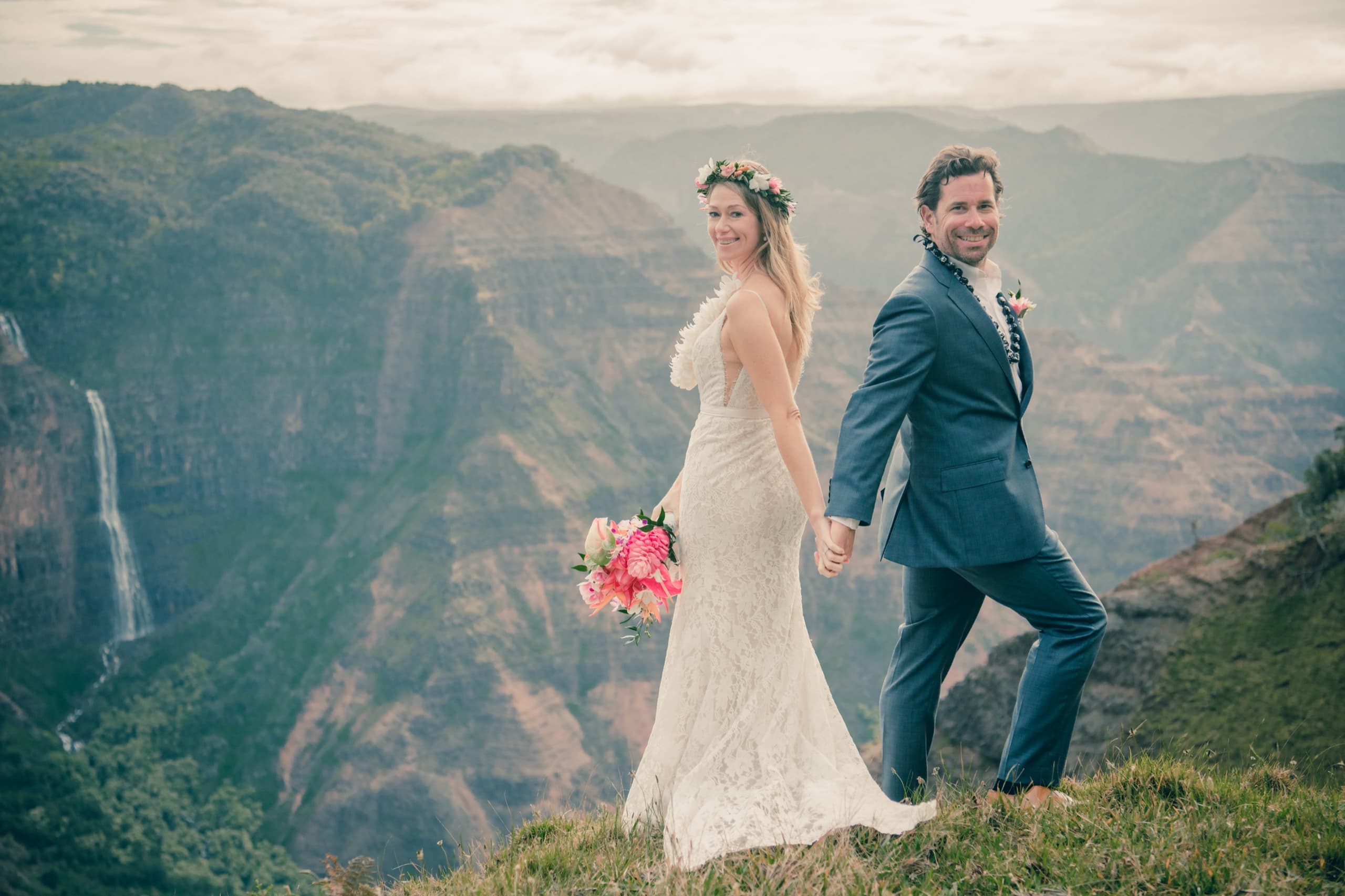 Erin leading Kenny by the hand along the ridge above Waimea Canyon, both turning back to the camera