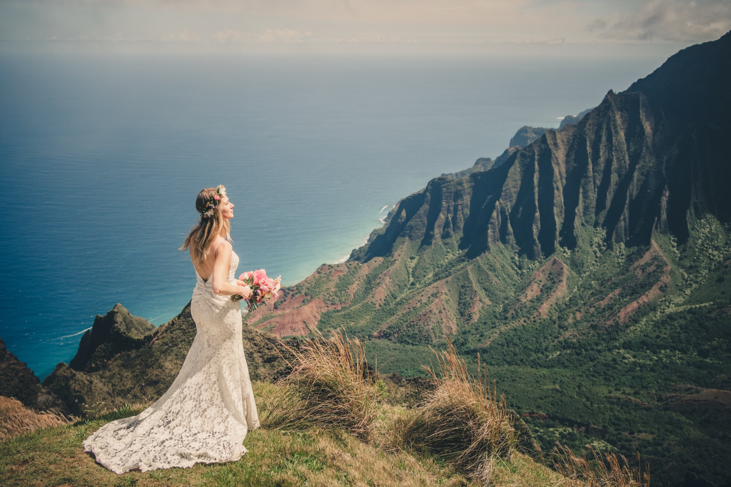 Erin standing alone at the Kalalau Lookout, looking out over the Na Pali Coast in her lace gown