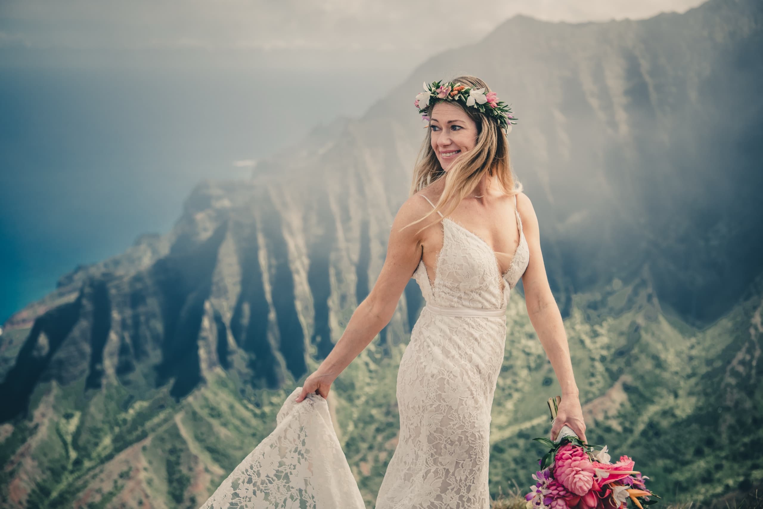 Bridal portrait of Erin smiling with the misty Na Pali ridges fading behind her