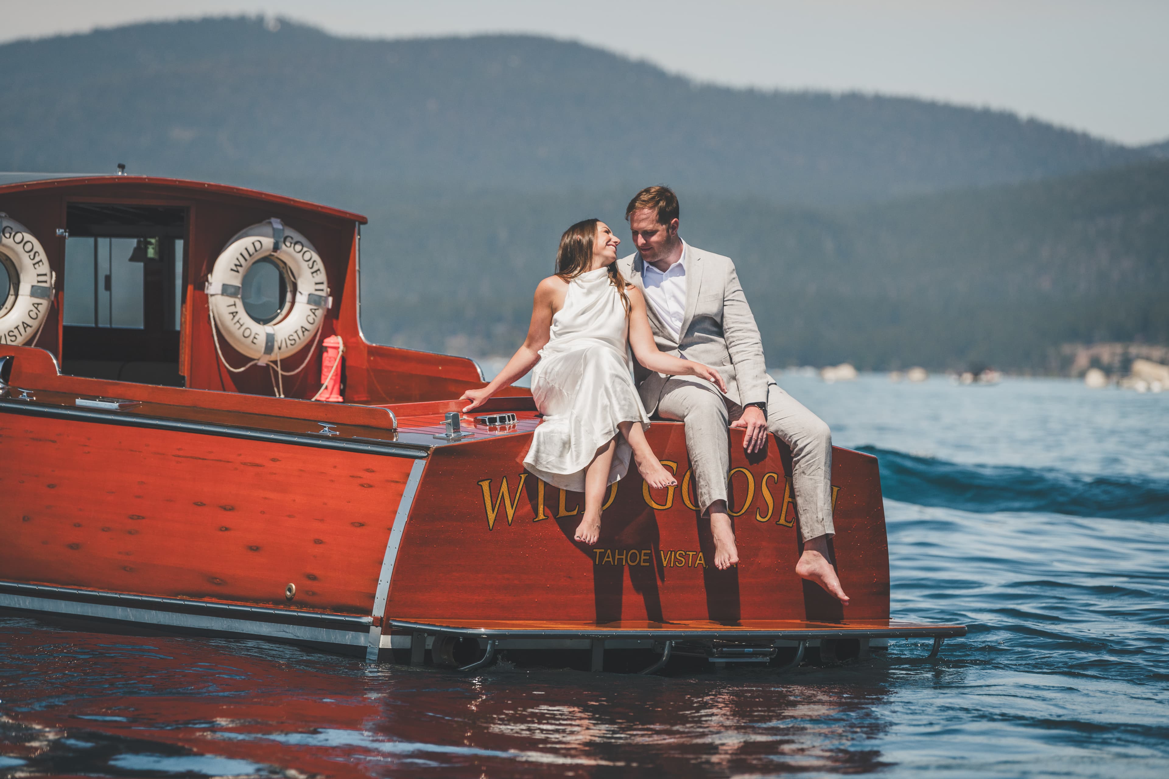 Hannah and Will sitting on the stern of a classic mahogany Tahoe boat during their first look on Lake Tahoe