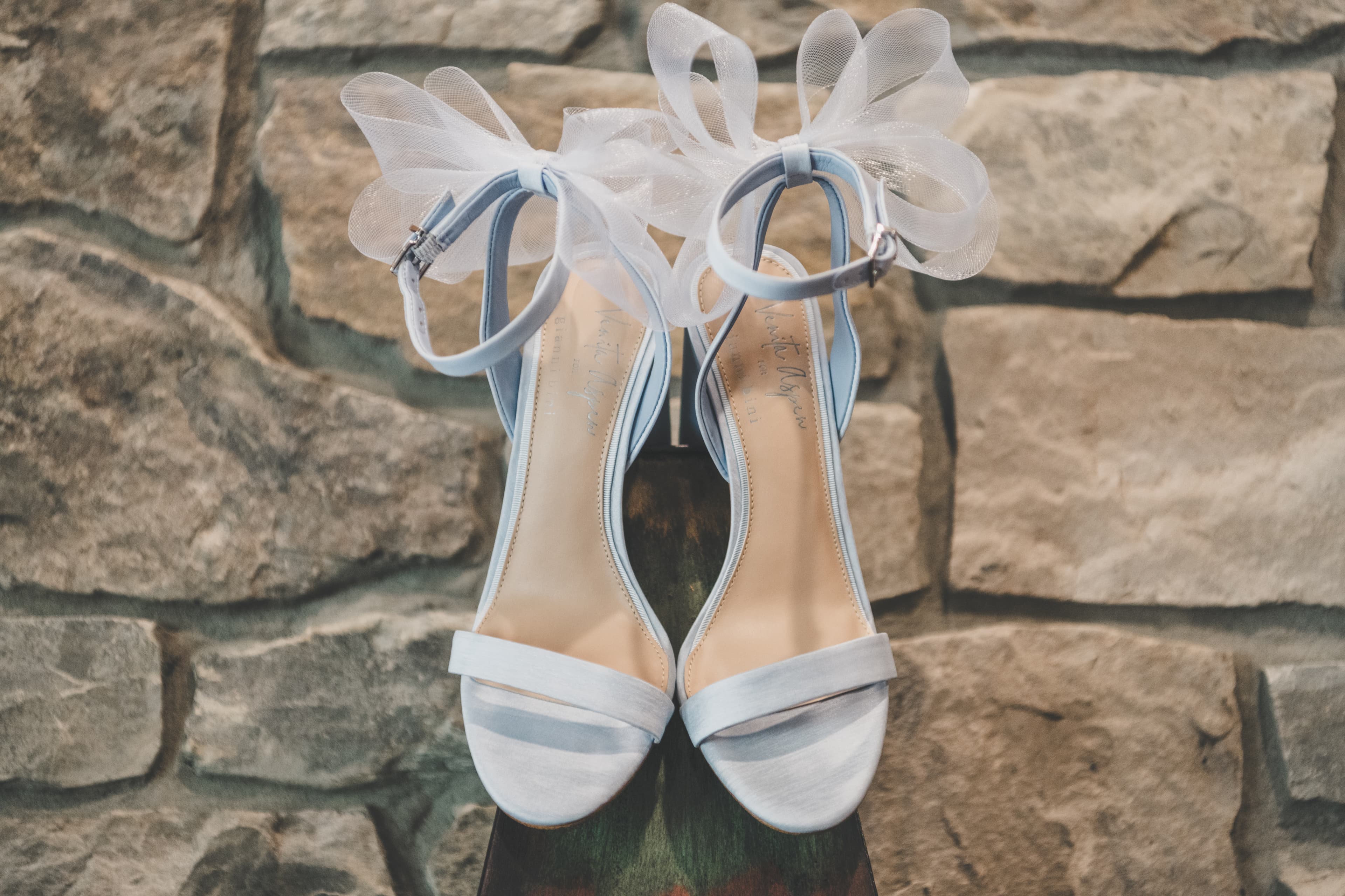 Hannah's pale blue heels with sheer bow ties resting against the Everline stone wall