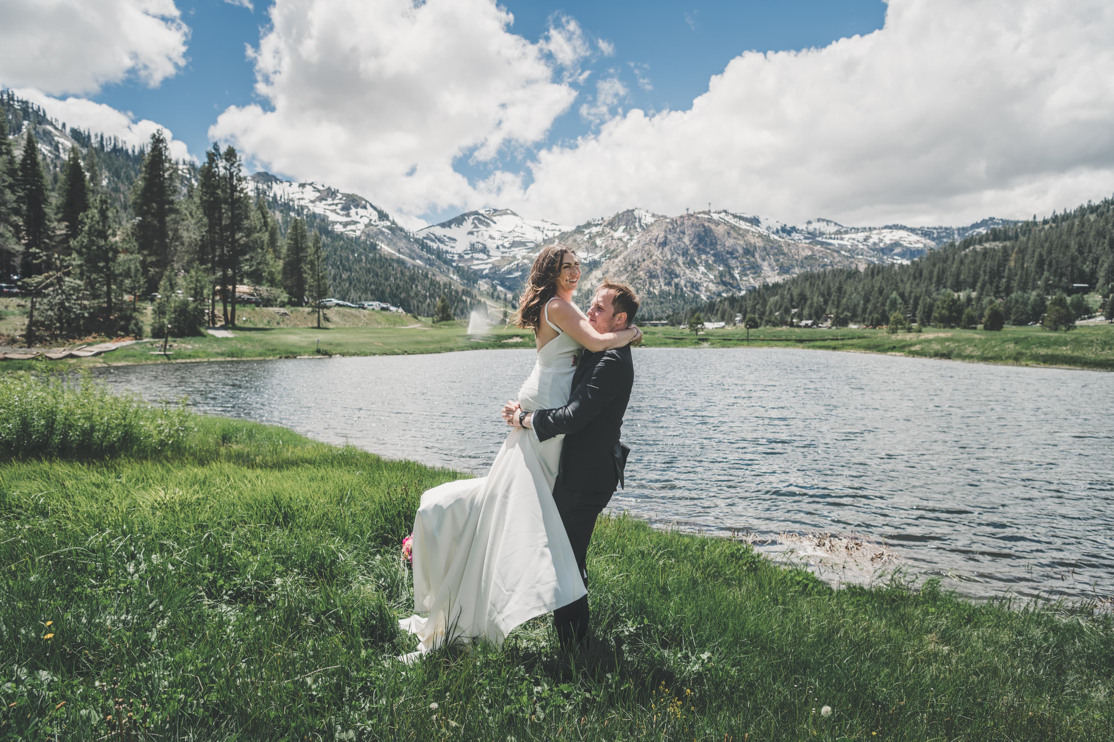 Will lifting Hannah at the lake's edge with the snow-streaked Palisades range filling the frame behind them