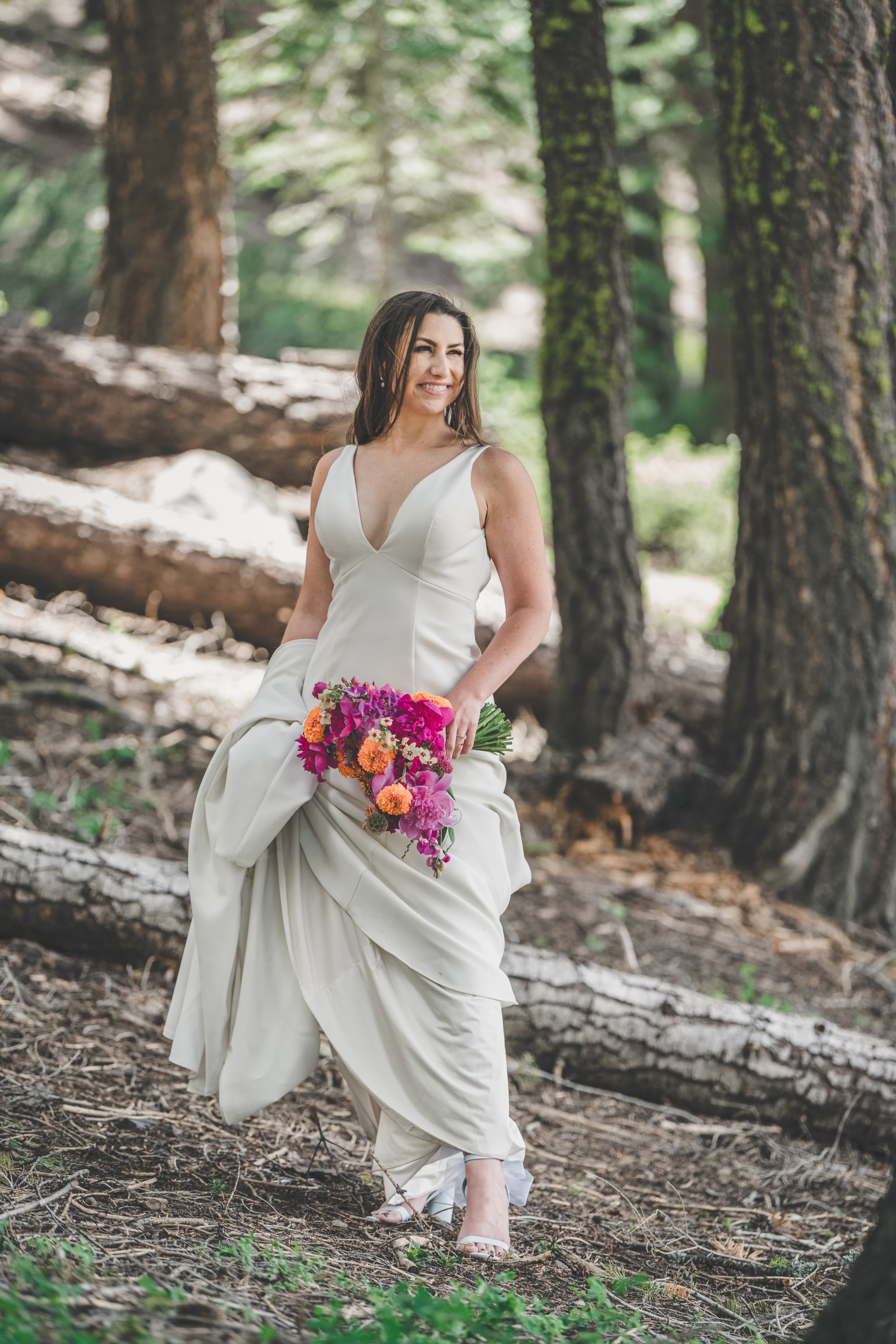 Hannah walking through the pines with her bouquet on the way to the ceremony