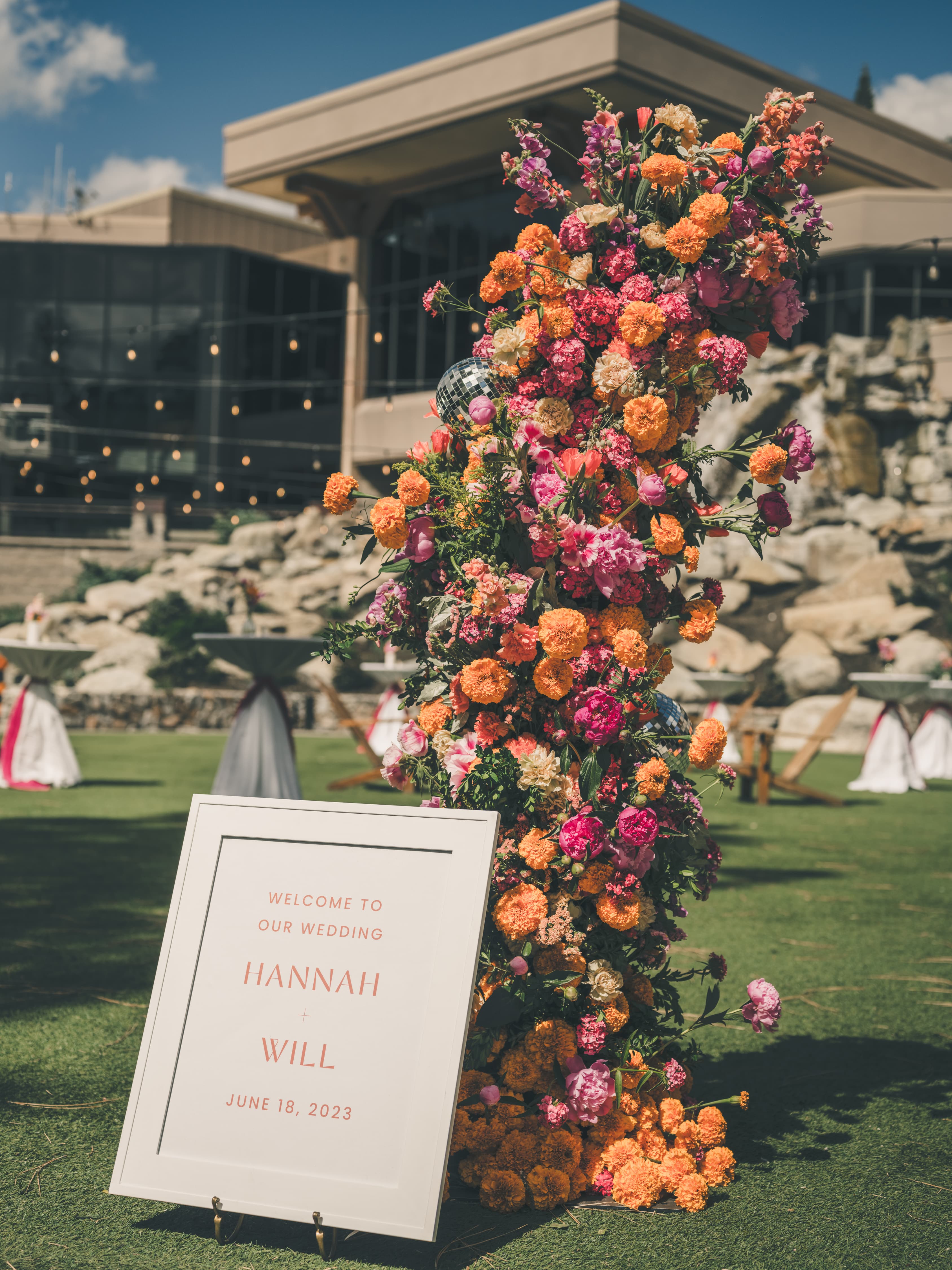 Welcome floral pillar reading 'Welcome to Our Wedding — Hannah & Will' on the lawn at Everline Resort