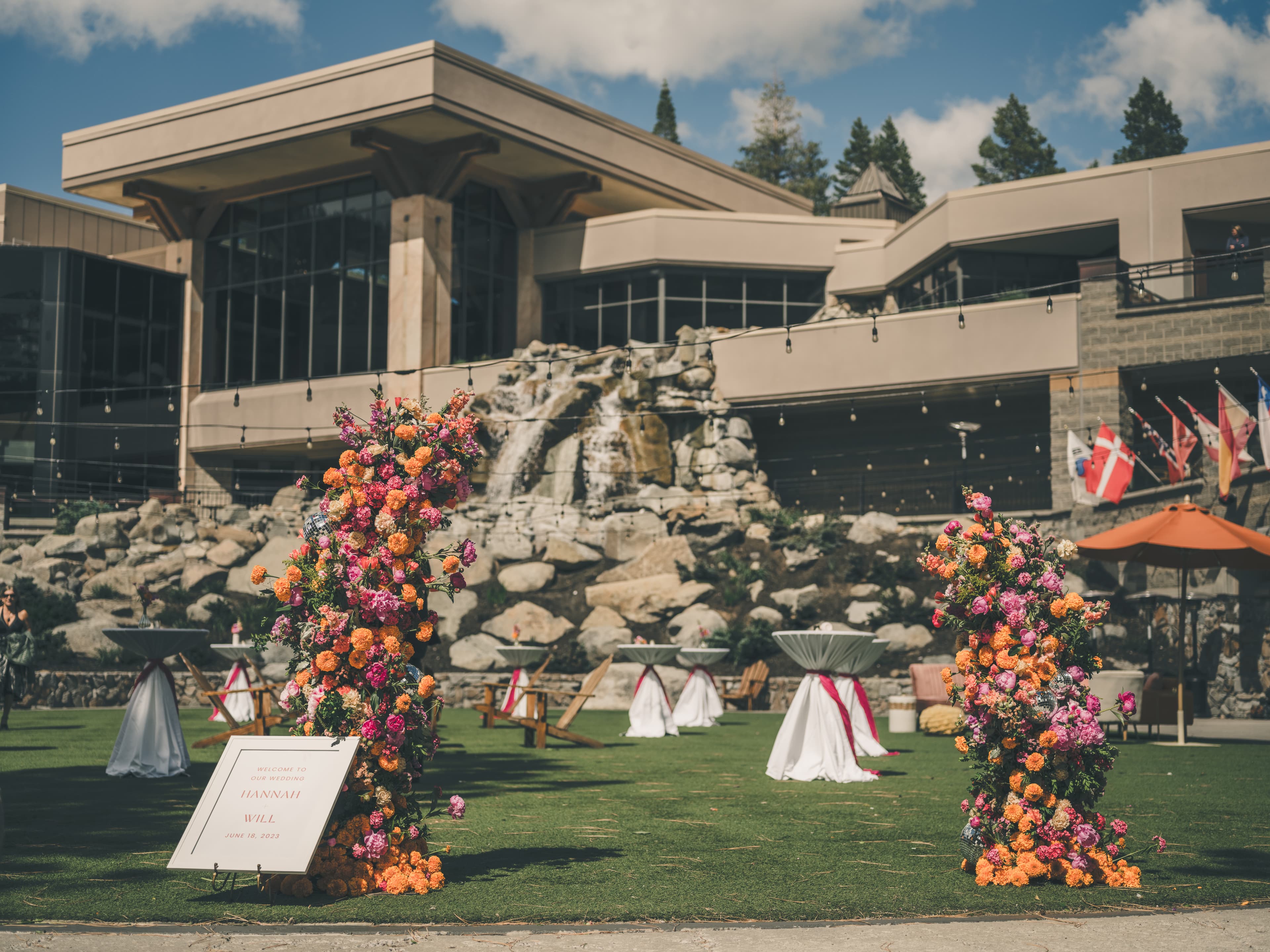Wide view of Everline Resort's stone-and-glass exterior with the rock waterfall feature and ceremony lawn ready for Hannah and Will's wedding