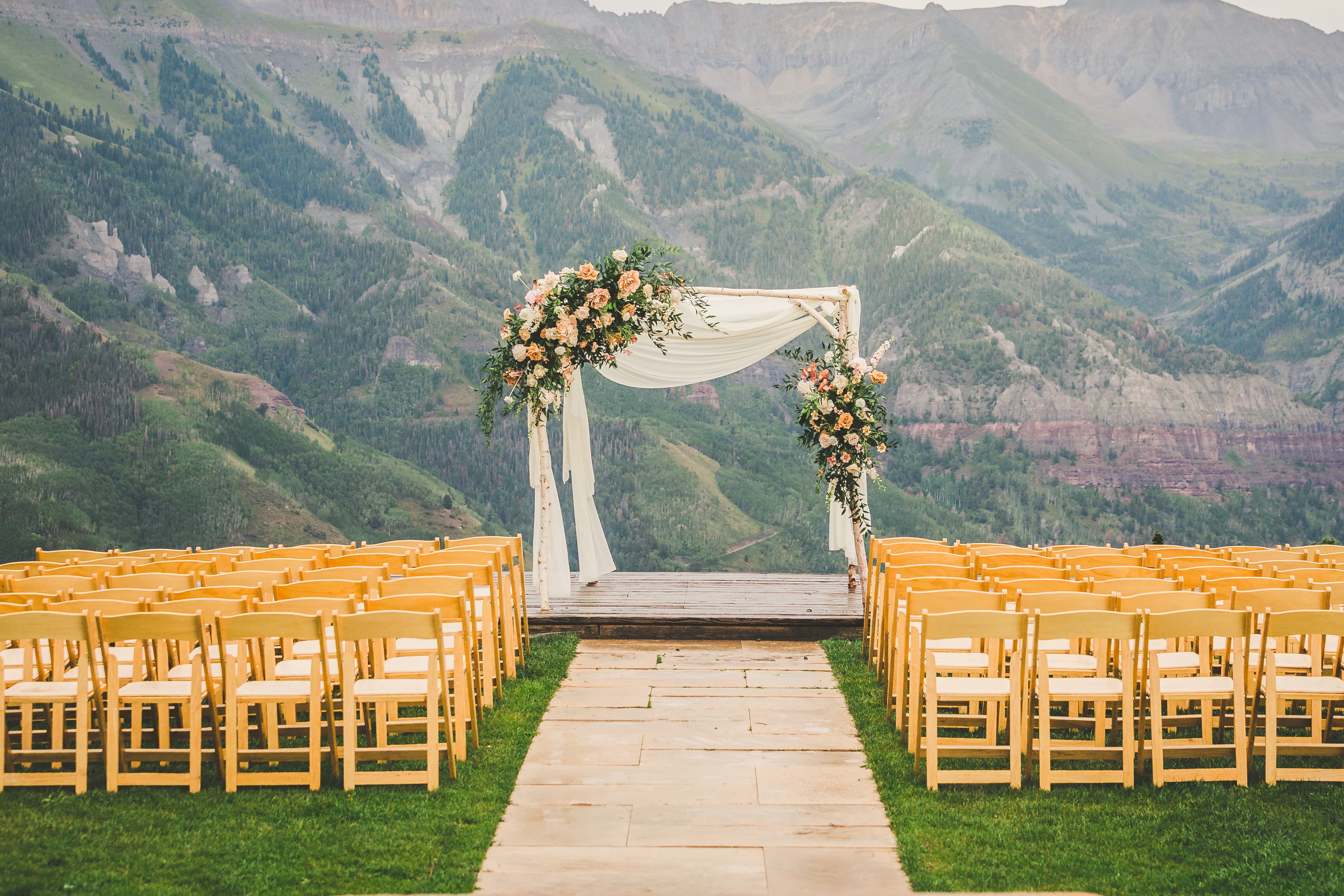 The empty ceremony deck at Allred's — flower arch altar, rows of wooden chairs, San Juan Mountains stretching behind