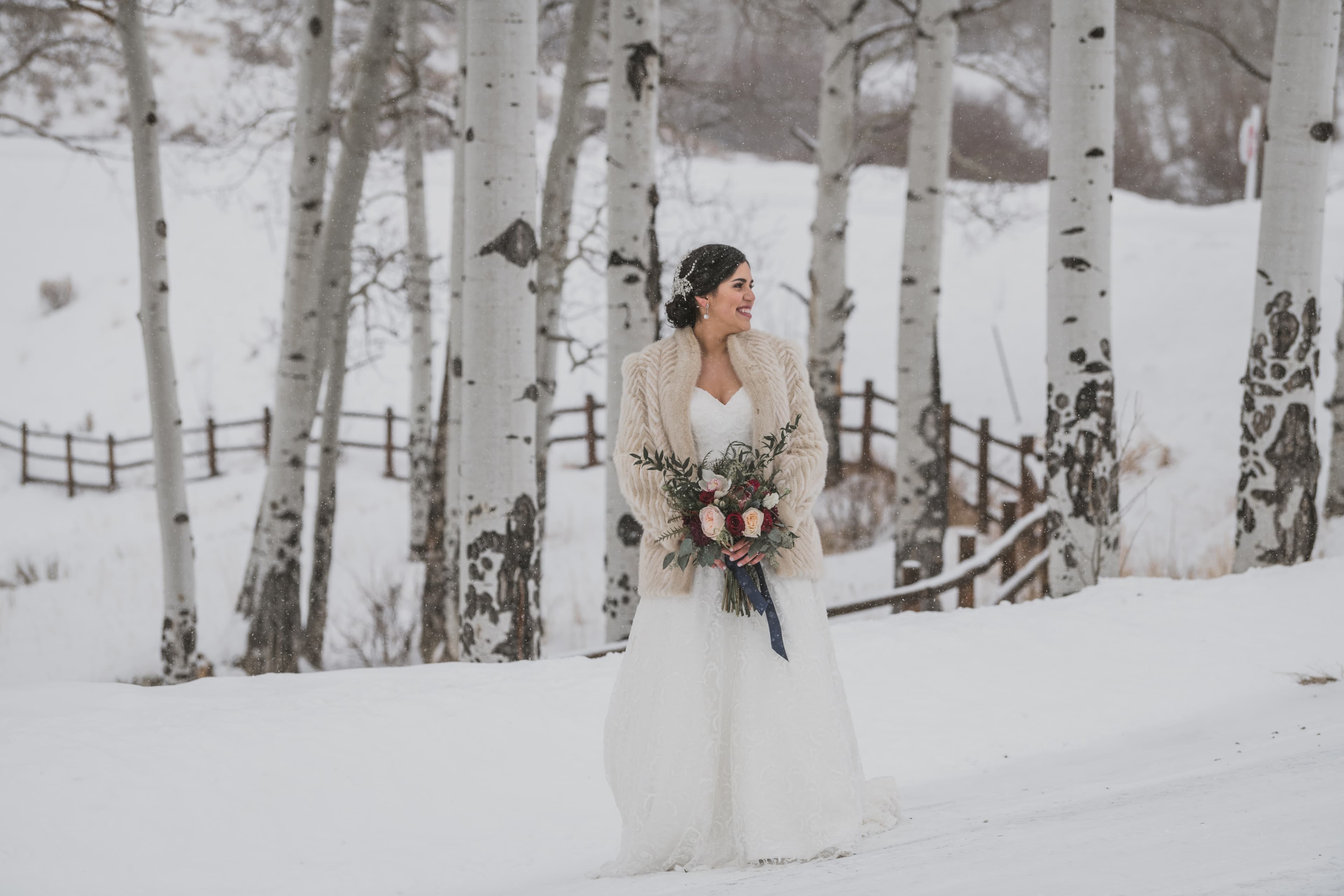 Sabrina with her bouquet beside a snow-covered split-rail fence in Telluride