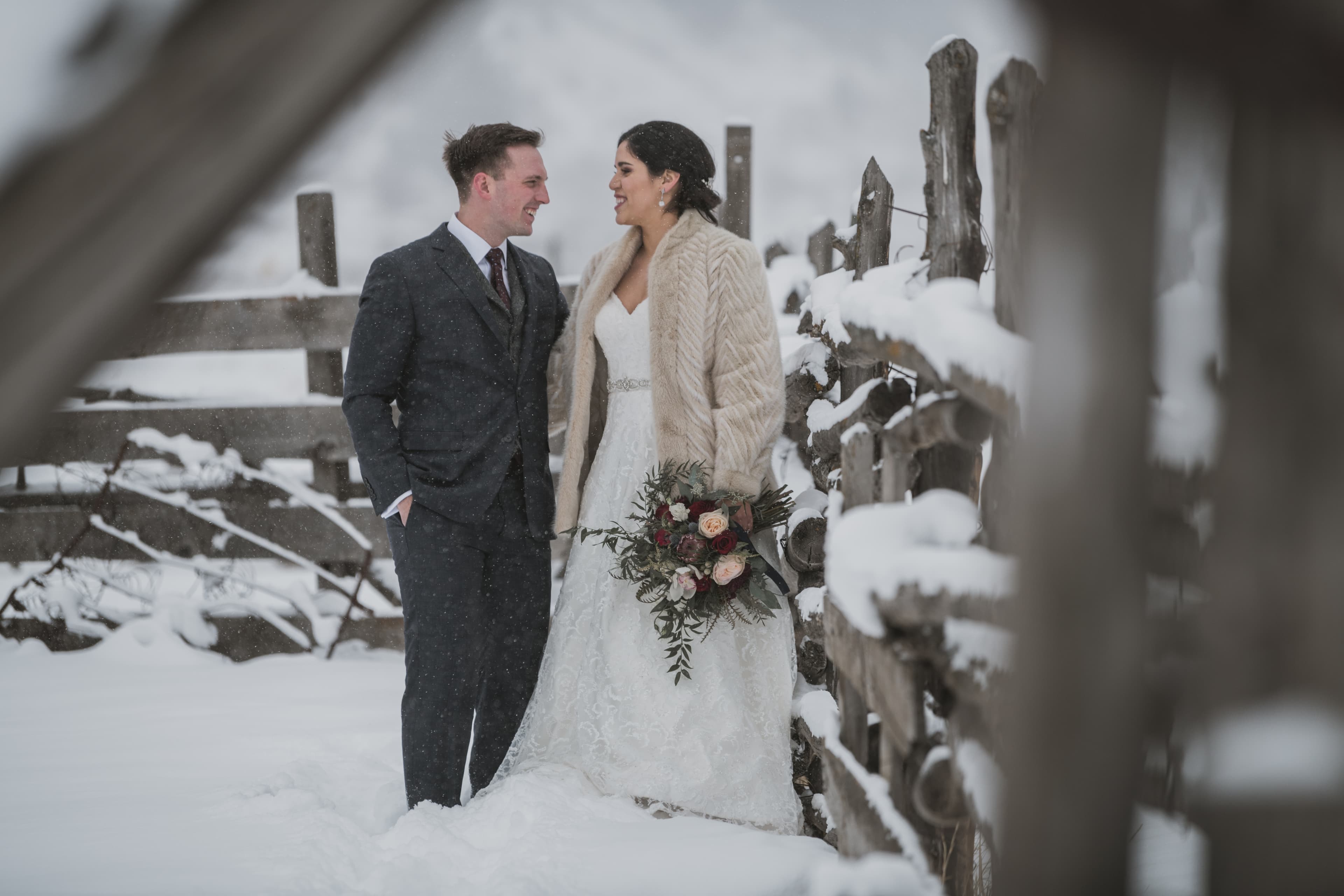 Sabrina and Patrick stand by a snow-covered fence on their Telluride wedding day