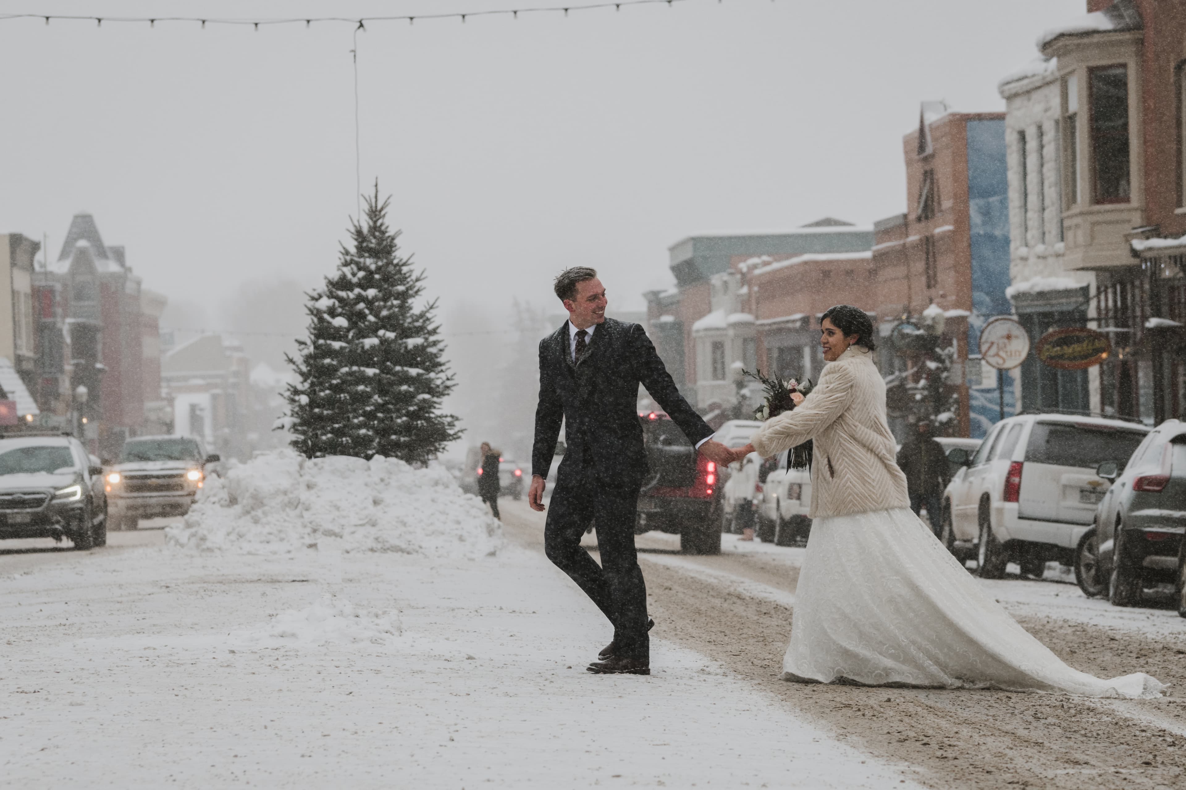 Sabrina and Patrick holding hands on Telluride's snowy main street under string lights