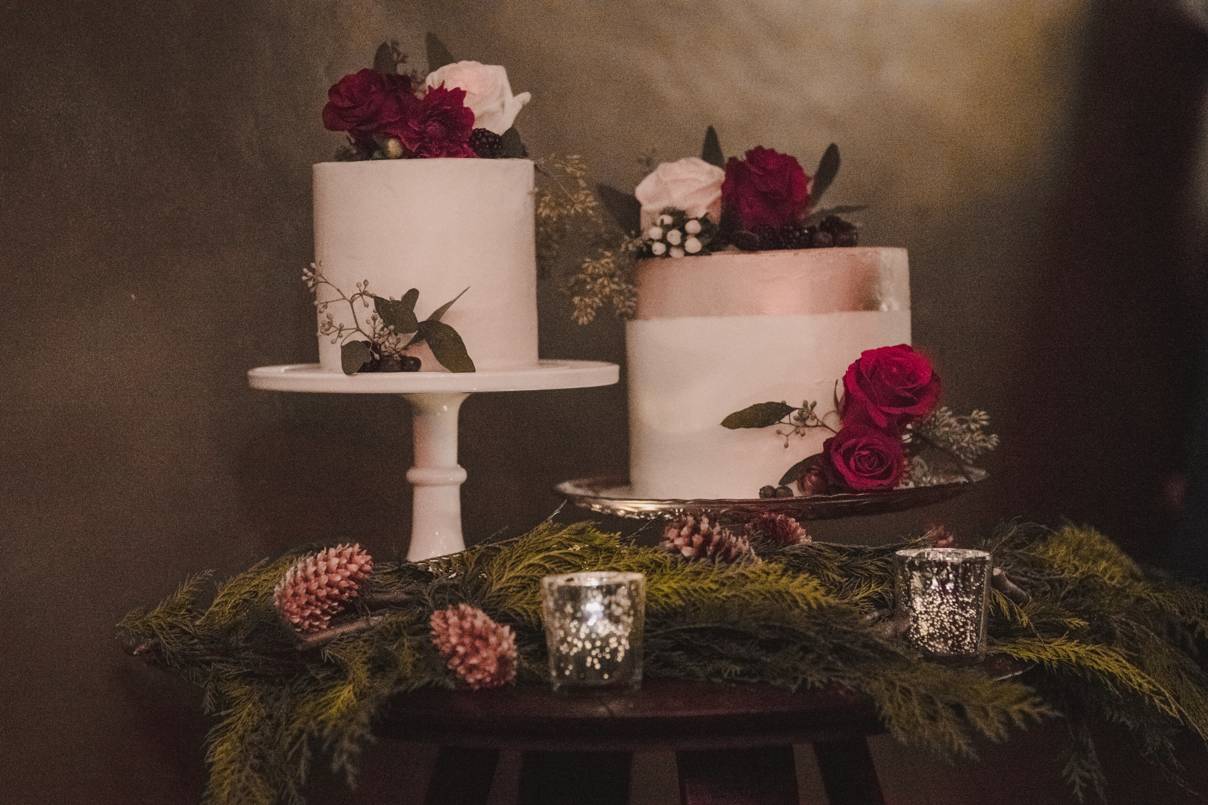 Sabrina and Patrick's two-tier wedding cake with red roses and winter greenery at Alpino Vino