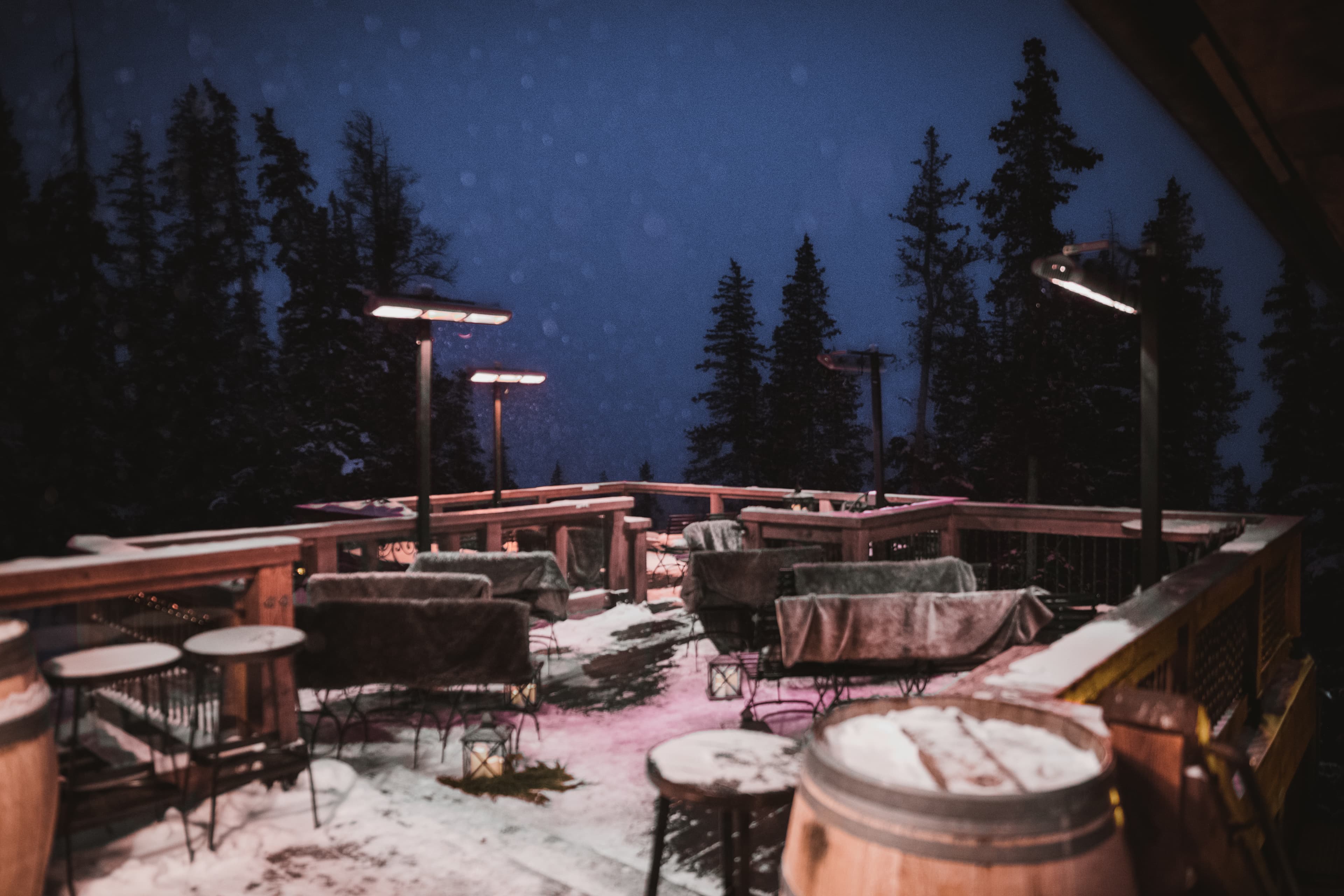 The Alpino Vino deck at twilight — heat lamps, lanterns and snow-dusted seating at 11,966 feet