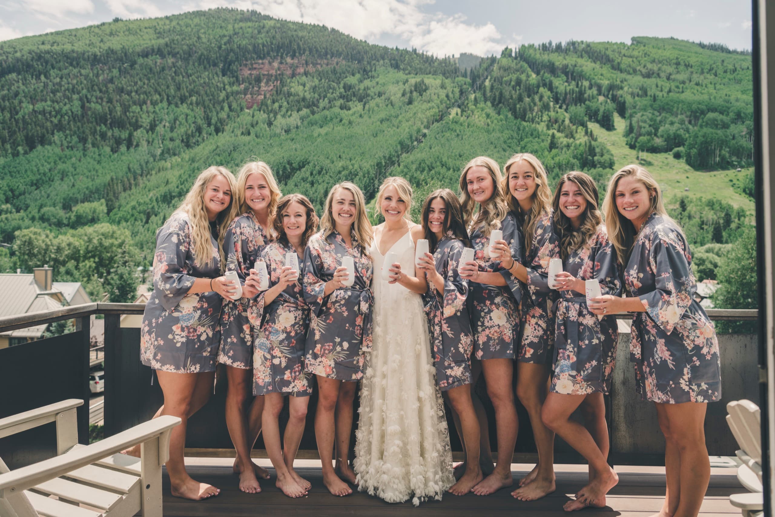Meghan and her bridesmaids in matching floral robes laughing on the Gorrono Ranch deck before the ceremony