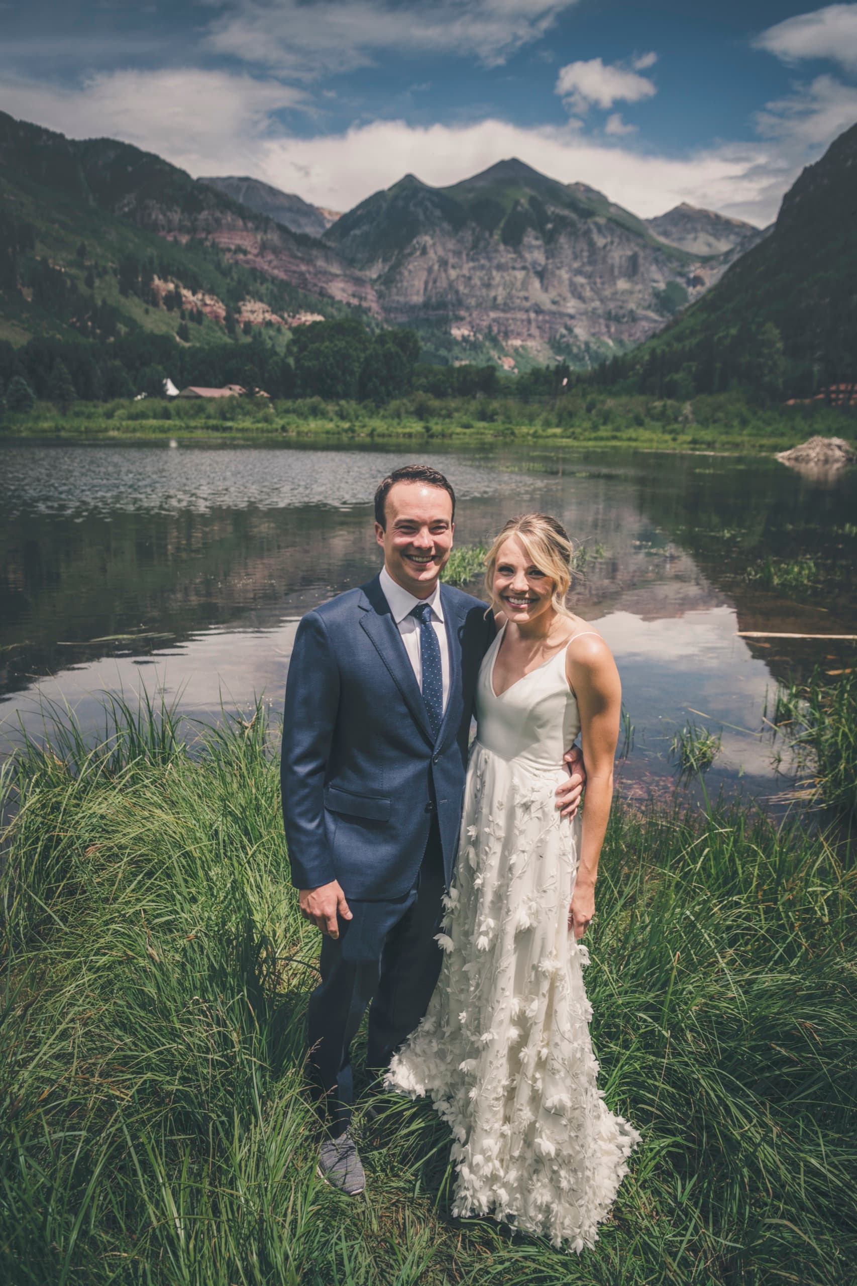 Meghan and Brent portrait in tall grass beside a pond with the Telluride box canyon peaks behind them