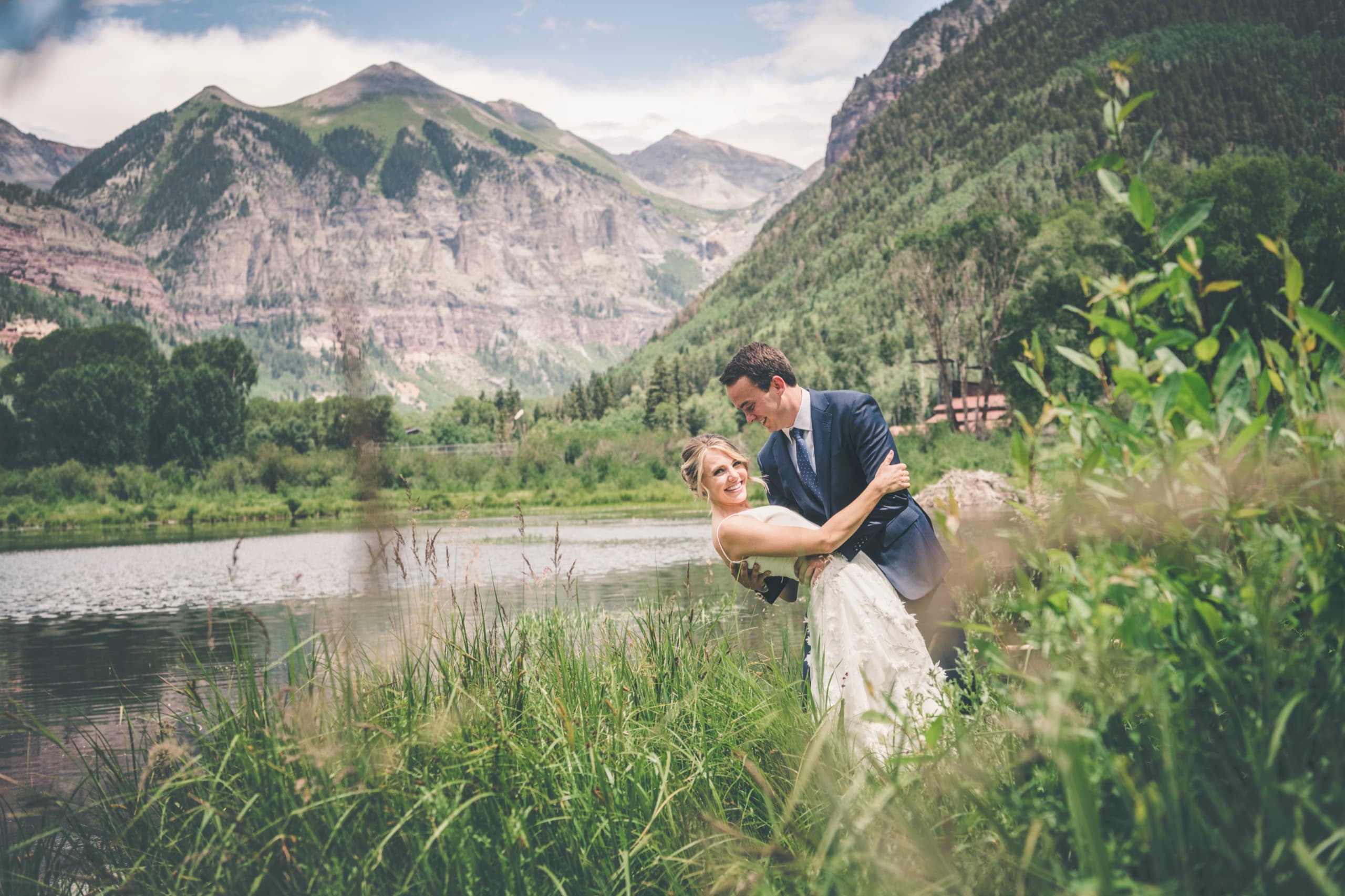 Meghan and Brent laughing through a playful dip beside the pond, Telluride peaks and aspens behind