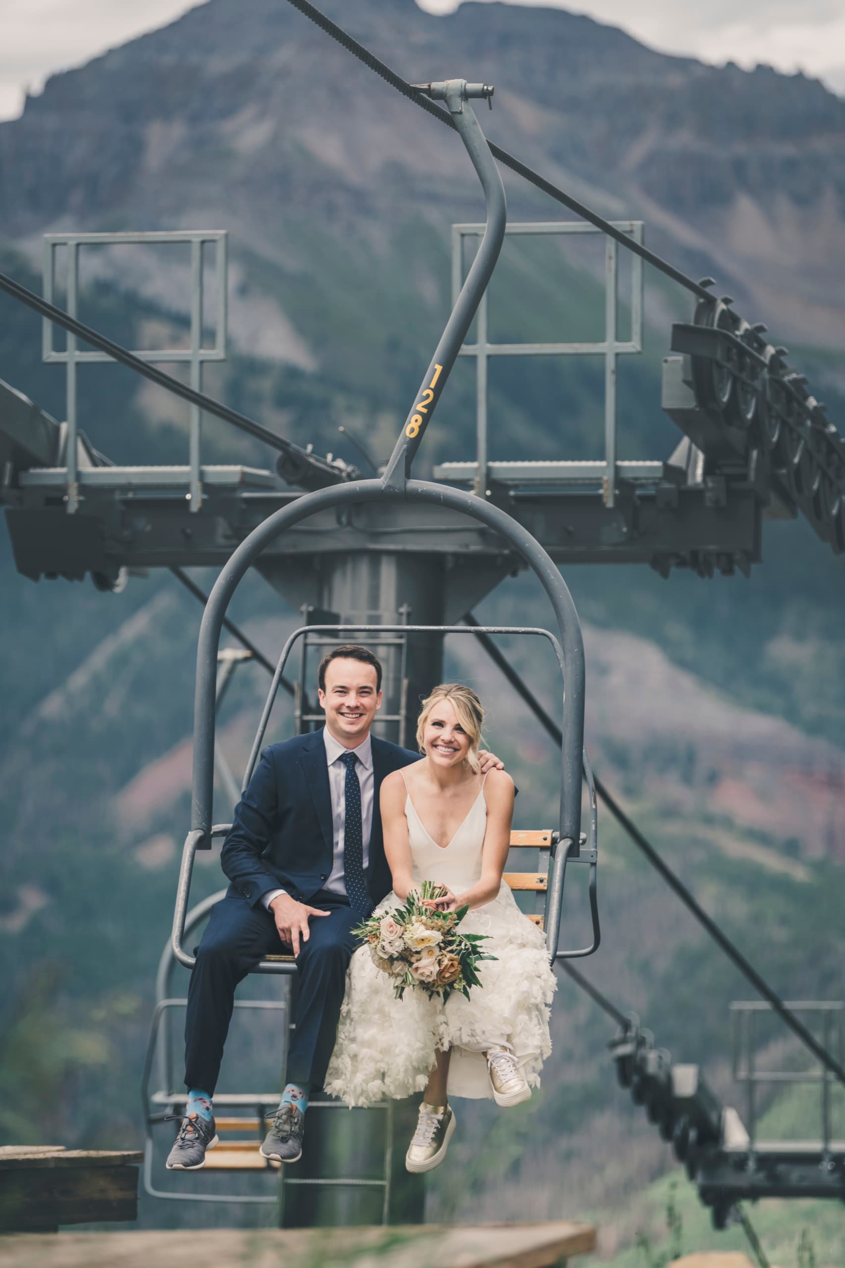 Meghan and Brent seated together on a stationary chairlift high above the Telluride ridge