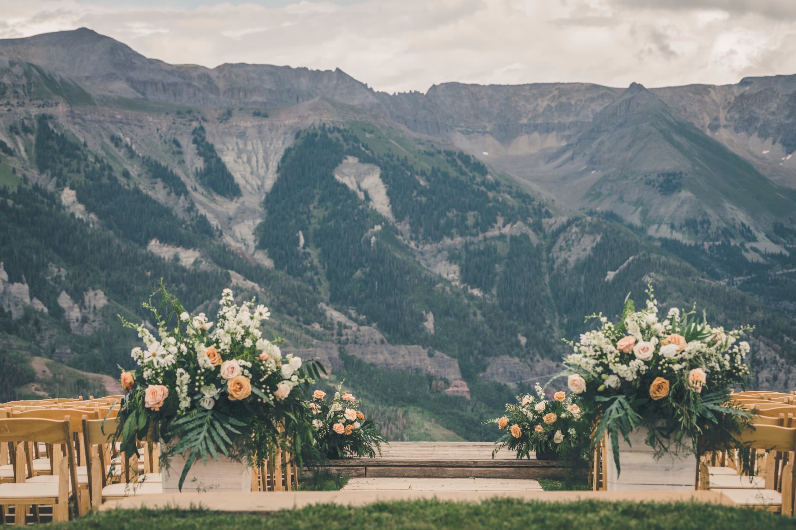 The empty meadow ceremony aisle at Gorrono Ranch with twin floral arrangements framing the San Sophia ridge view