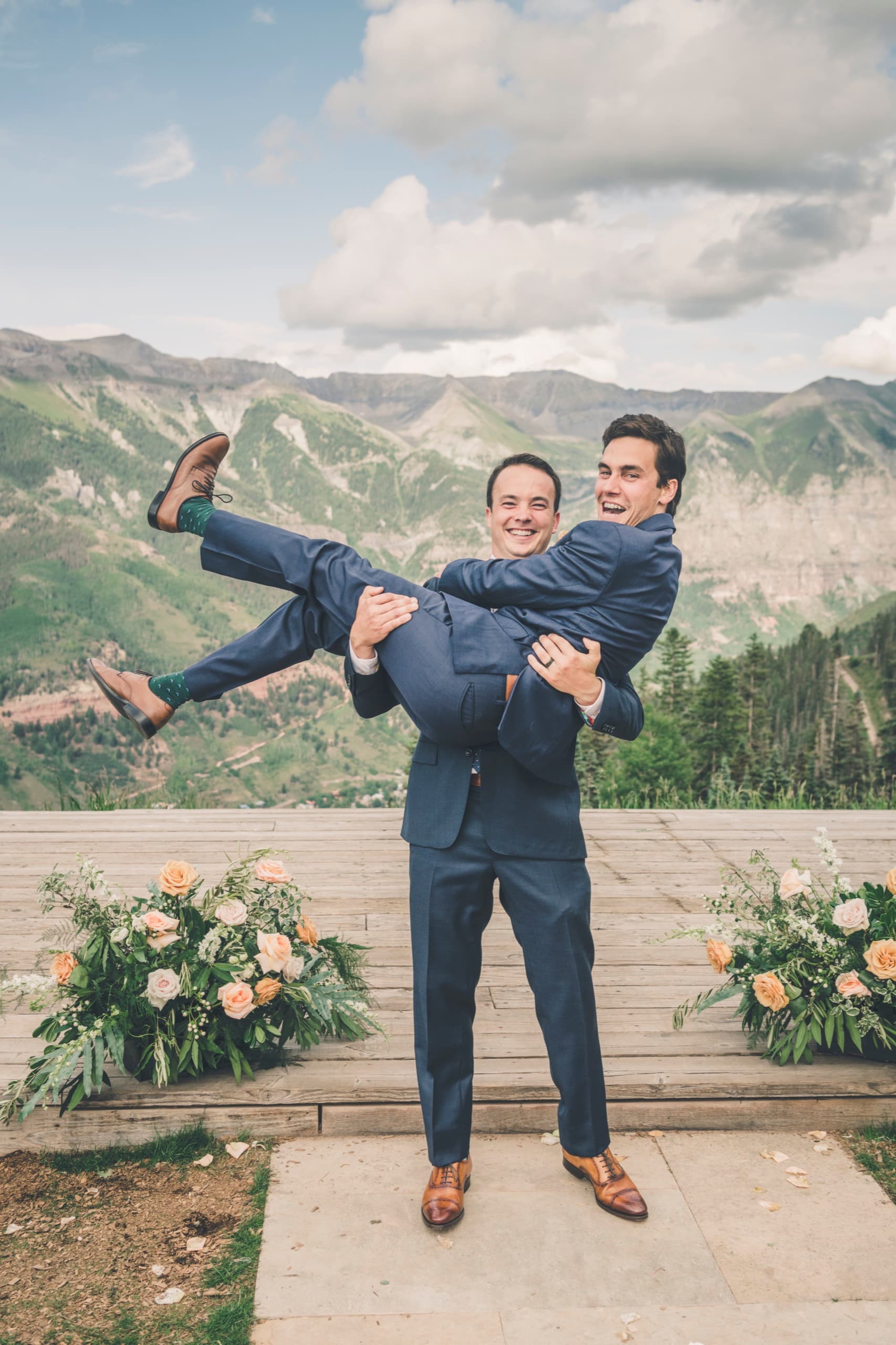 Two groomsmen carrying Brent horizontally like a log on the Gorrono Ranch deck, all of them laughing
