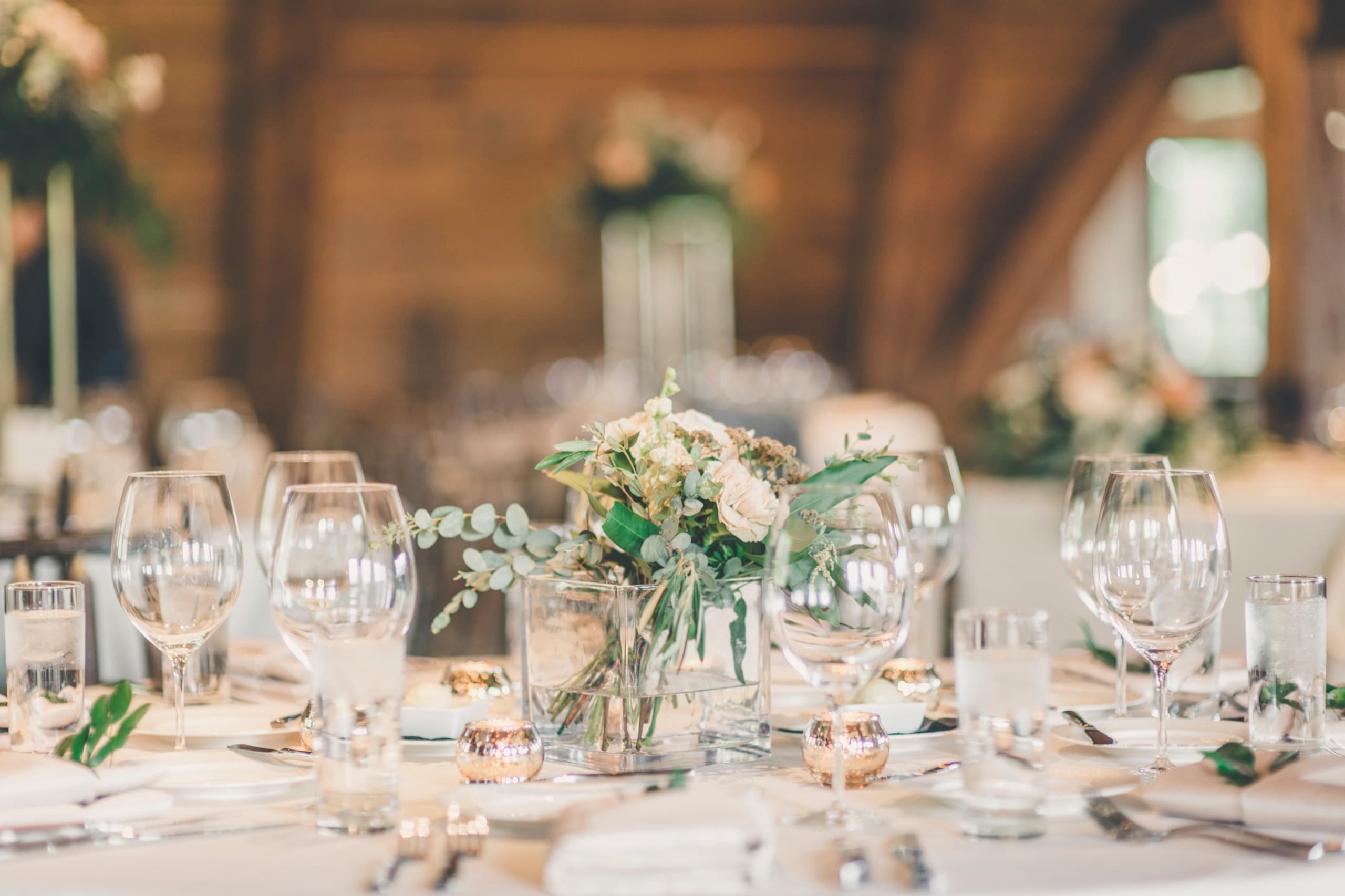 Soft-focus reception centerpiece — wine glasses, eucalyptus, candlelight in the Gorrono Ranch lodge
