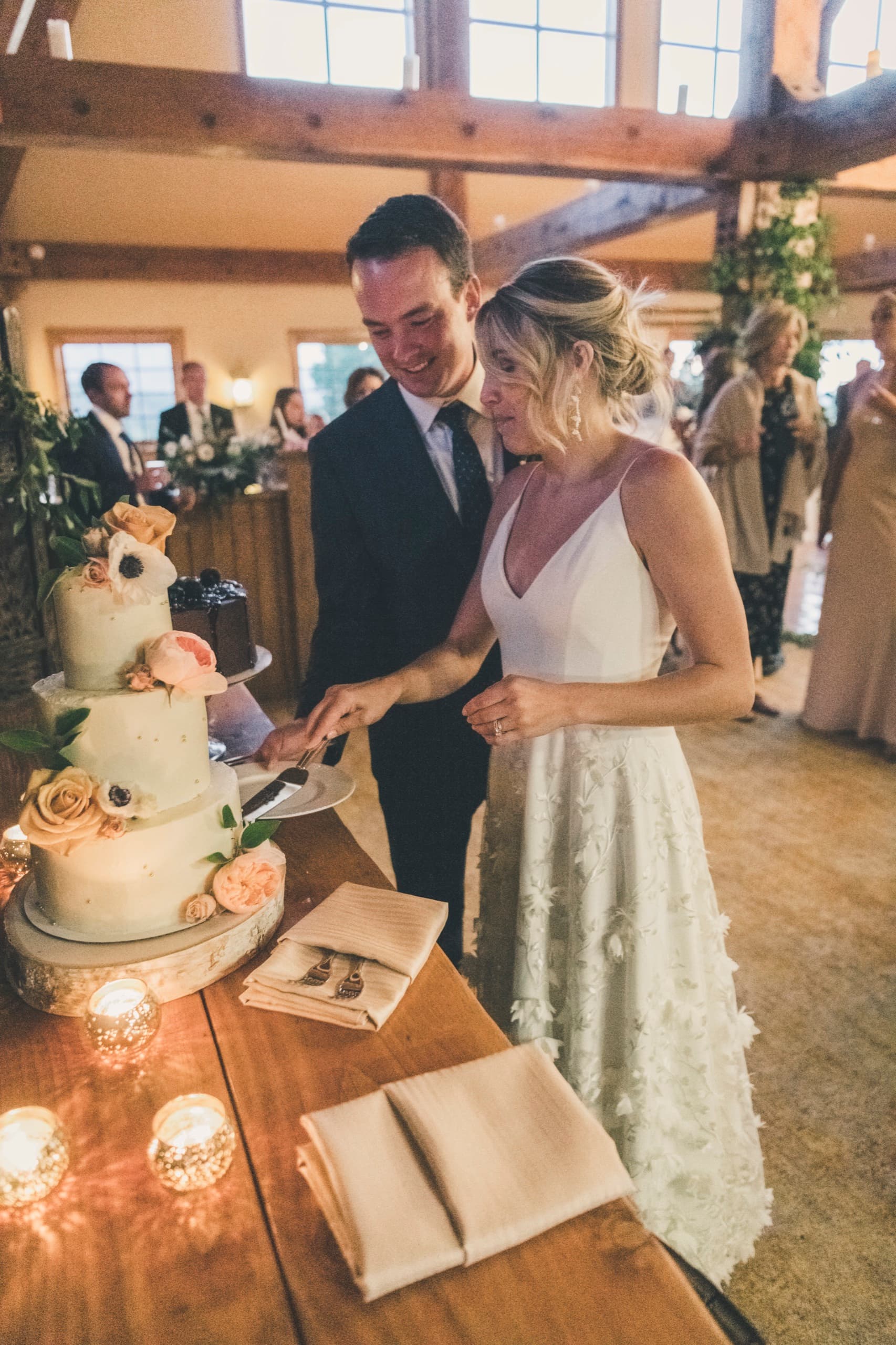 Meghan and Brent cutting their wedding cake inside the Gorrono Ranch lodge, intimate smiles, warm window light