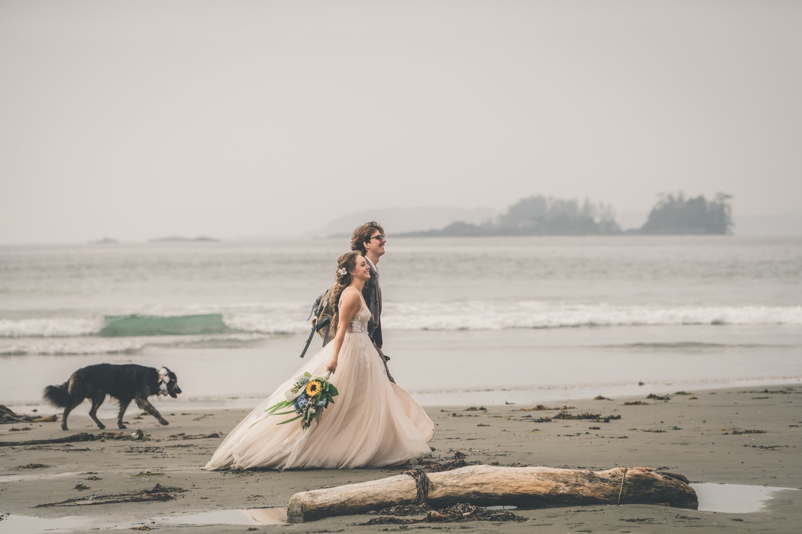 Rachel and Peter walking a foggy Tofino beach with their dog at their side