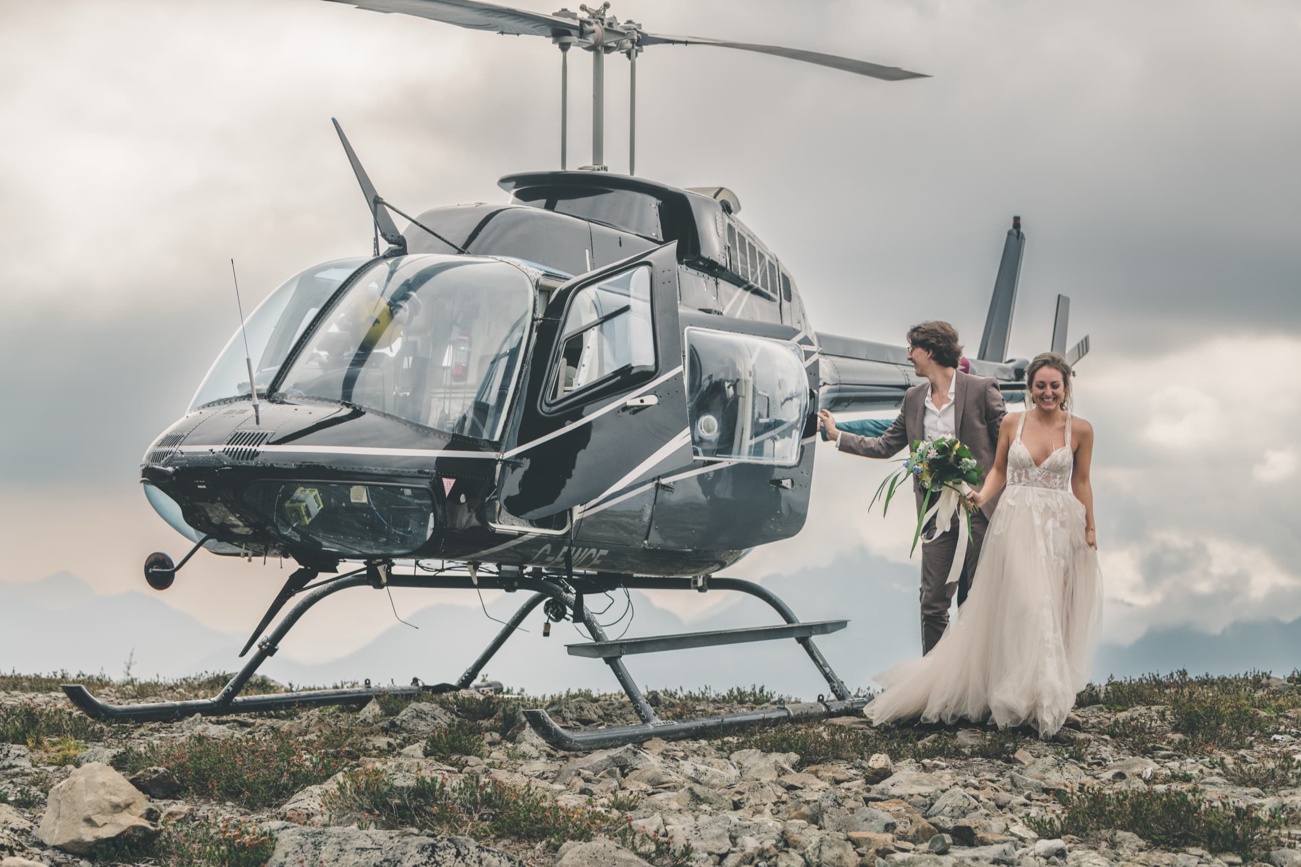 Rachel and Peter stepping out of the chartered helicopter onto an alpine ridge