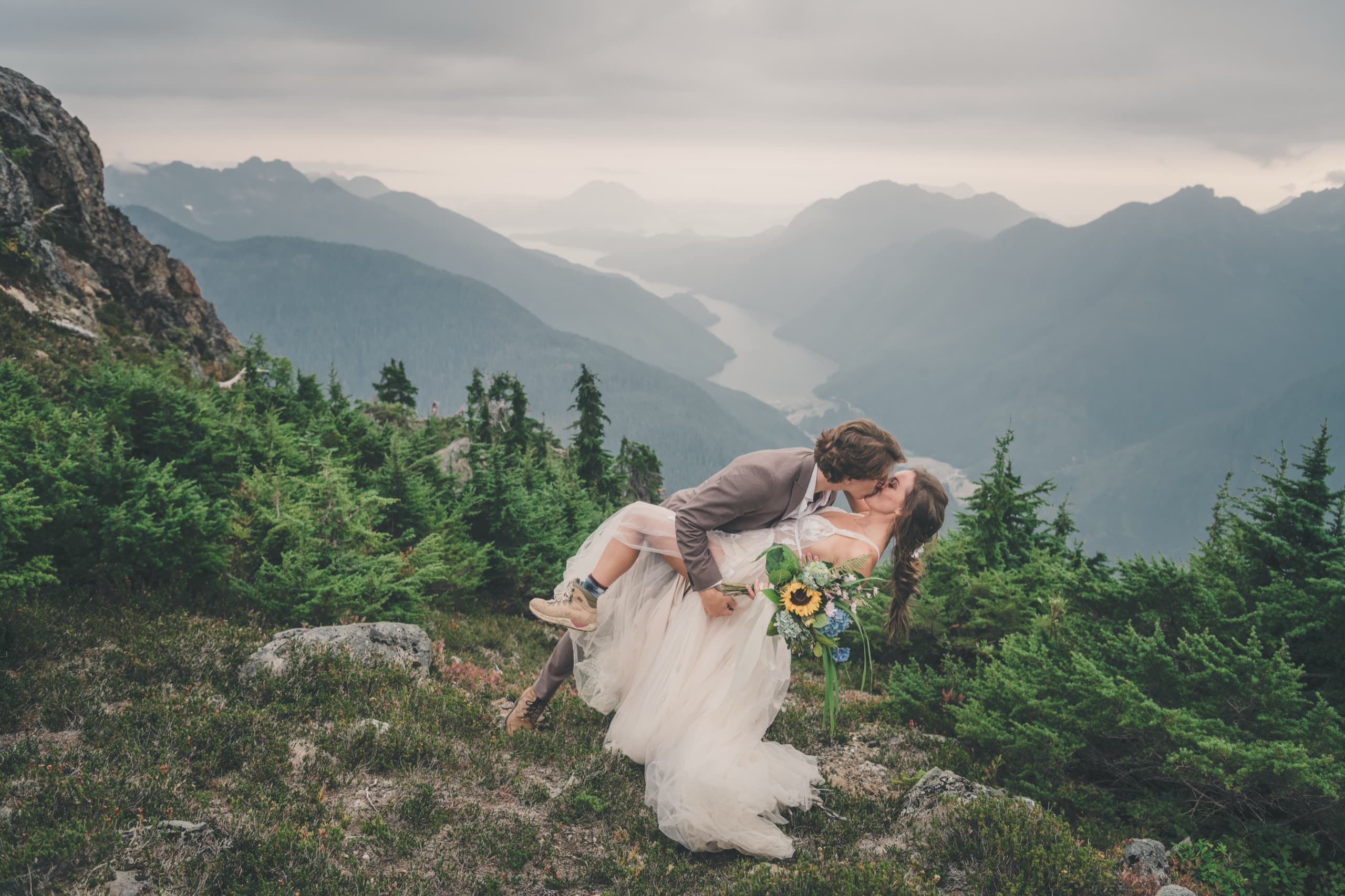 Rachel and Peter share a dip kiss on an alpine ridge above a deep Tofino fjord valley