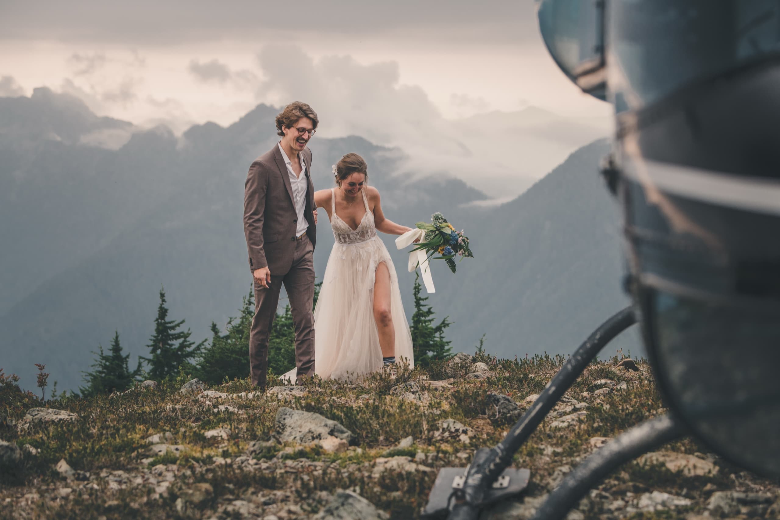 Rachel and Peter walking past the helicopter rotor in the alpine, candid laughter