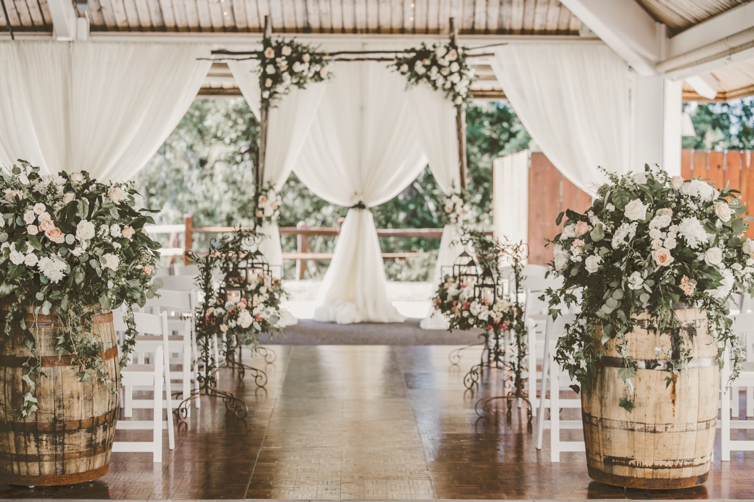 The Tenaya Lodge ceremony pavilion with white drapes, wine-barrel florals, and wood floor ready for the ceremony