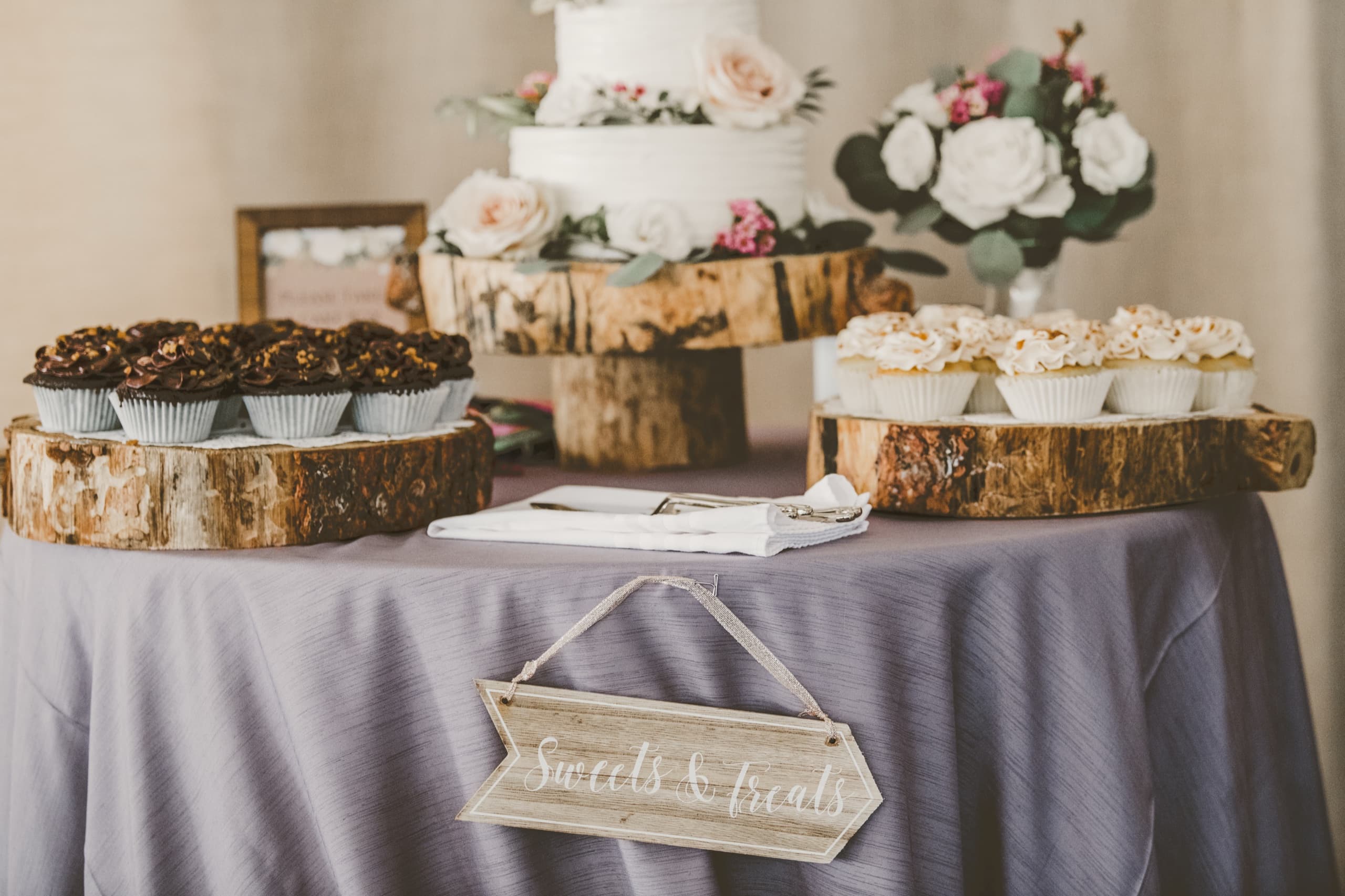 Jolly and Billy's Sweets and Treats dessert table with cake and cupcakes on wood slab risers