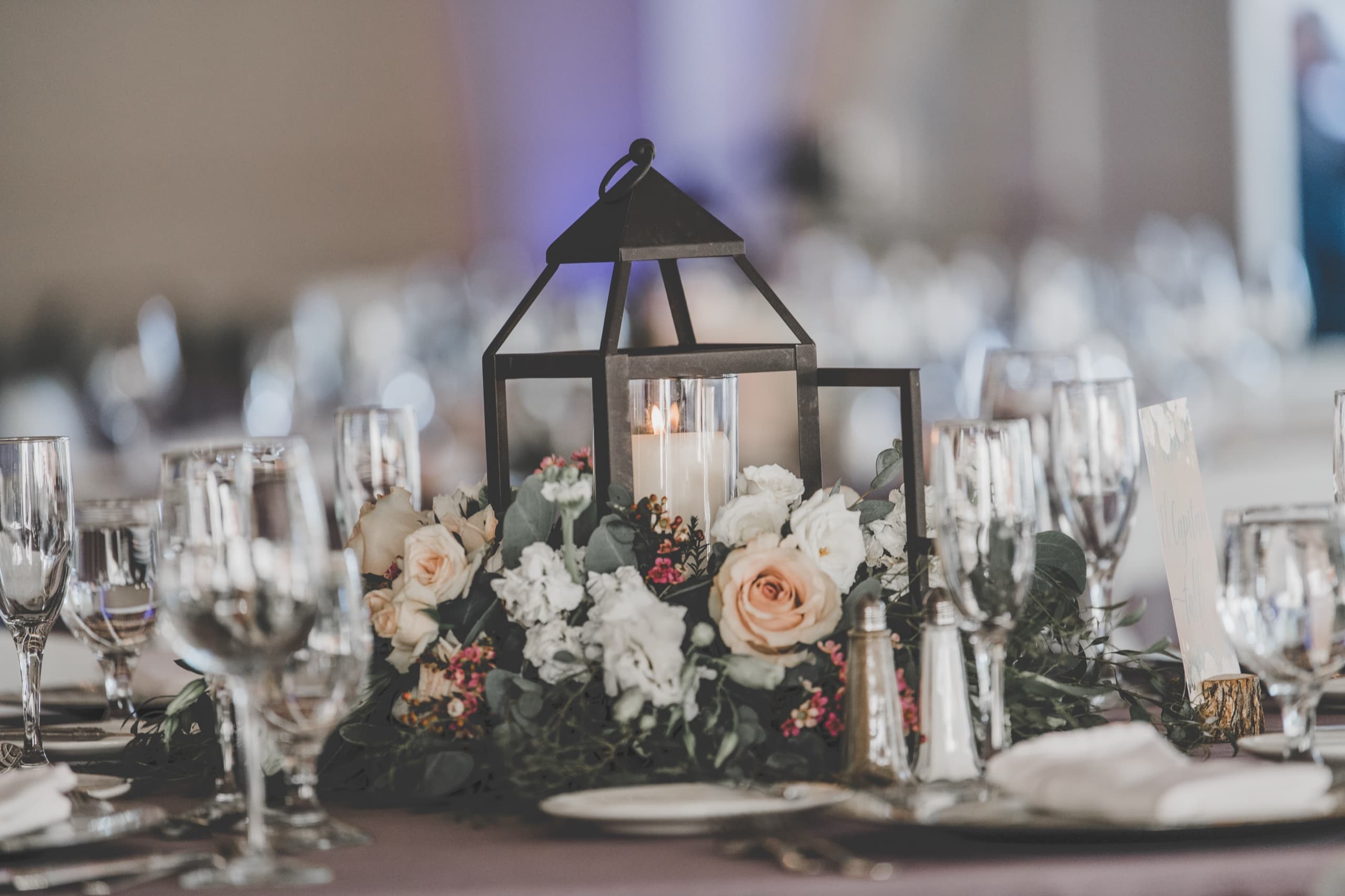 Reception table lantern centerpiece with roses among glassware in the indoor Tenaya ballroom