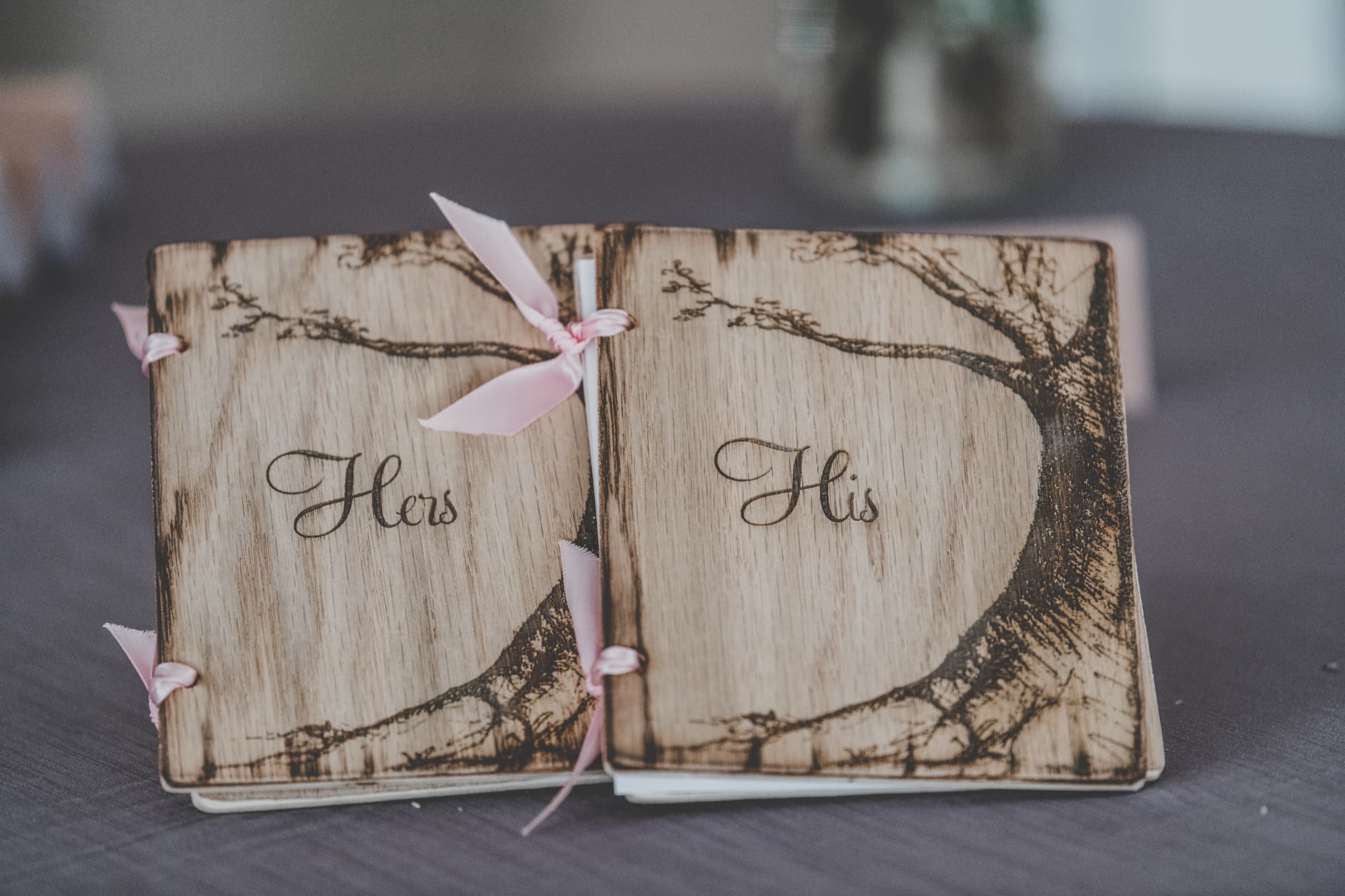 His and Hers wood vow books tied with pink ribbon at Jolly and Billy's sweetheart table