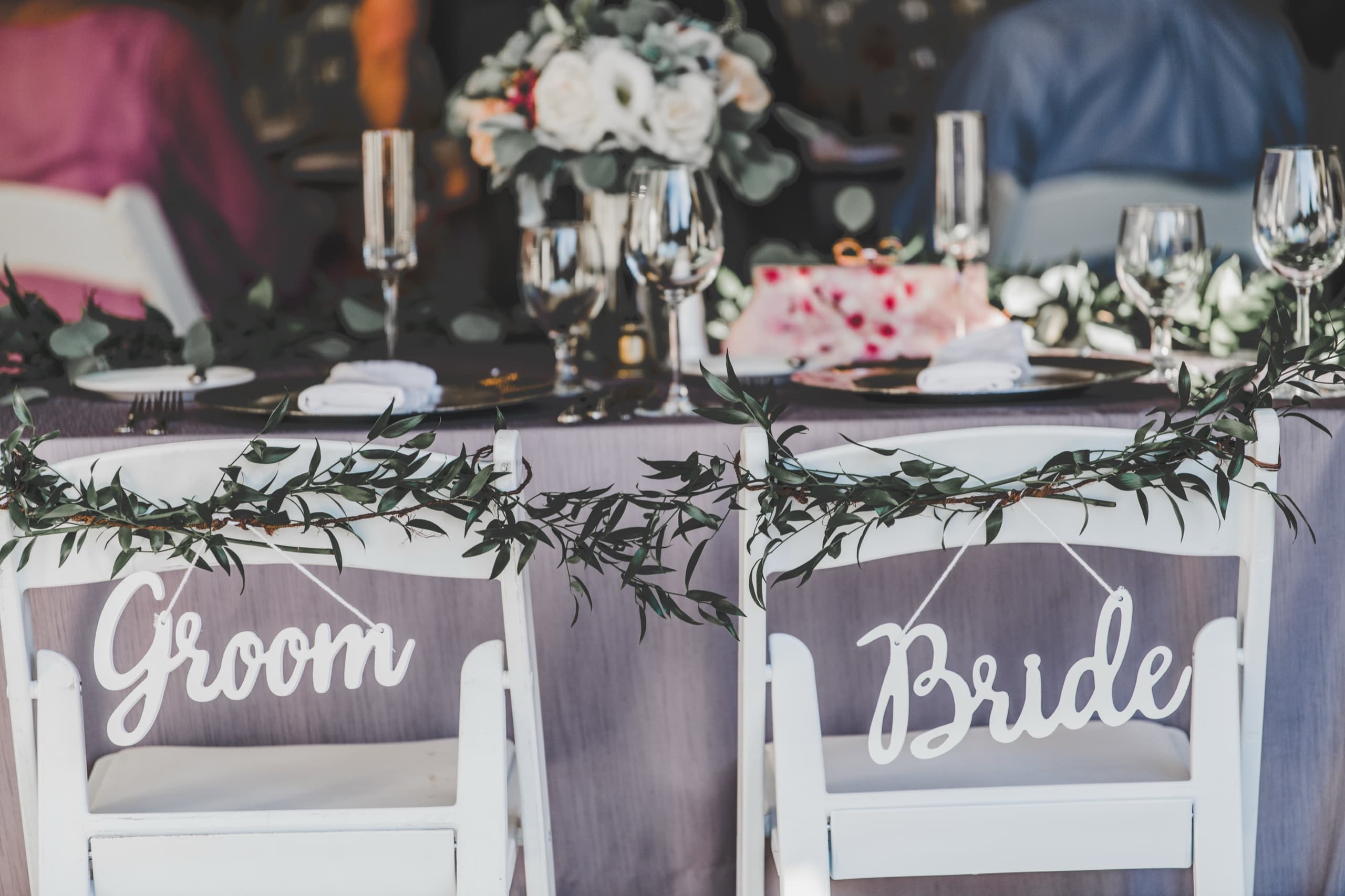 Bride and Groom chair signs draped in greenery garland at Jolly and Billy's sweetheart table